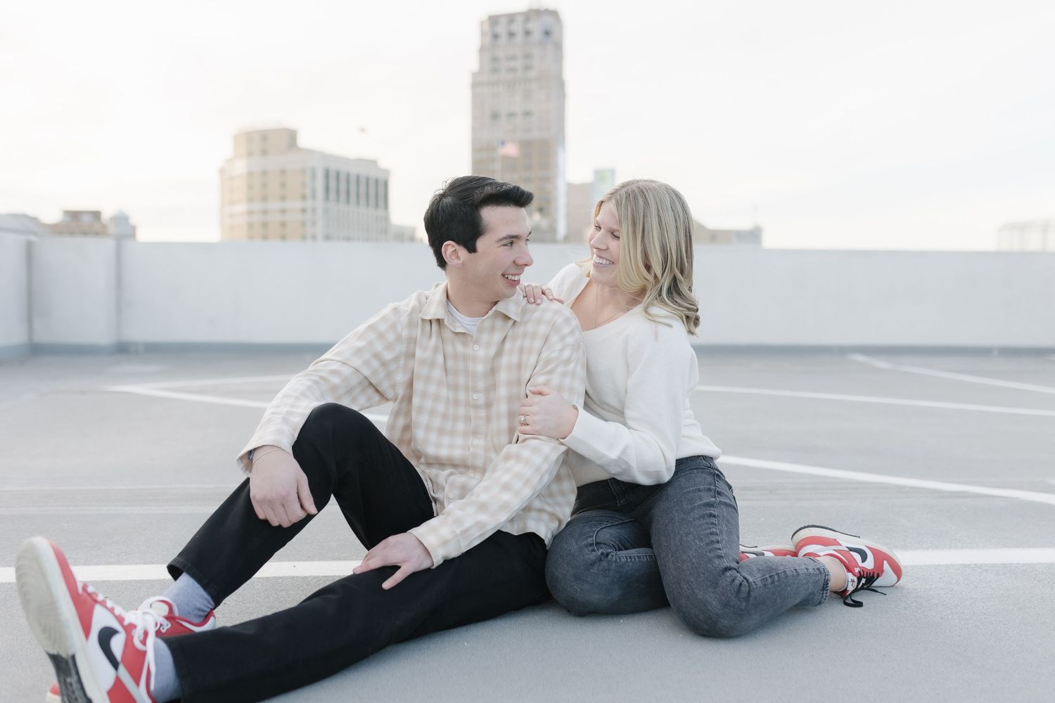 A tender moment between a couple sitting on an urban rooftop at sunset.