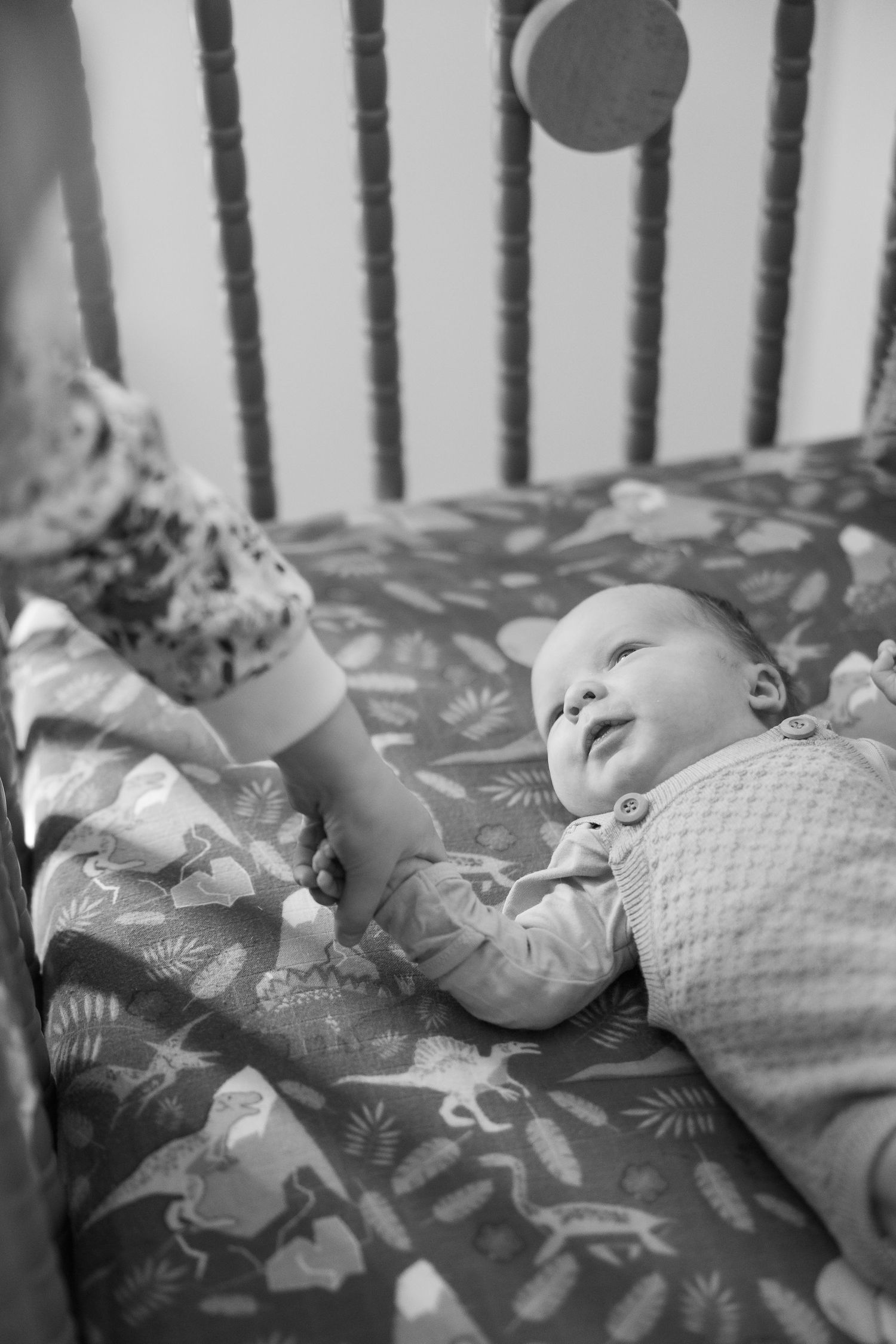 A sequence of black and white photos showing a baby yawning while lying on a patterned blanket.