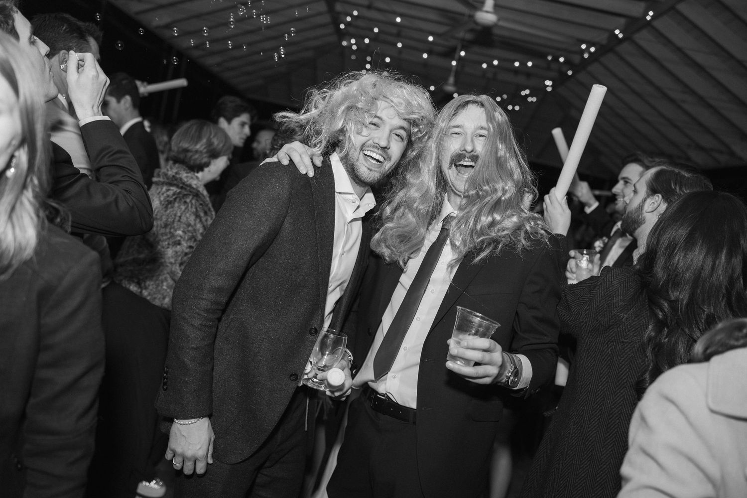 Black and white photo of party guests dancing and celebrating while wearing formal attire.