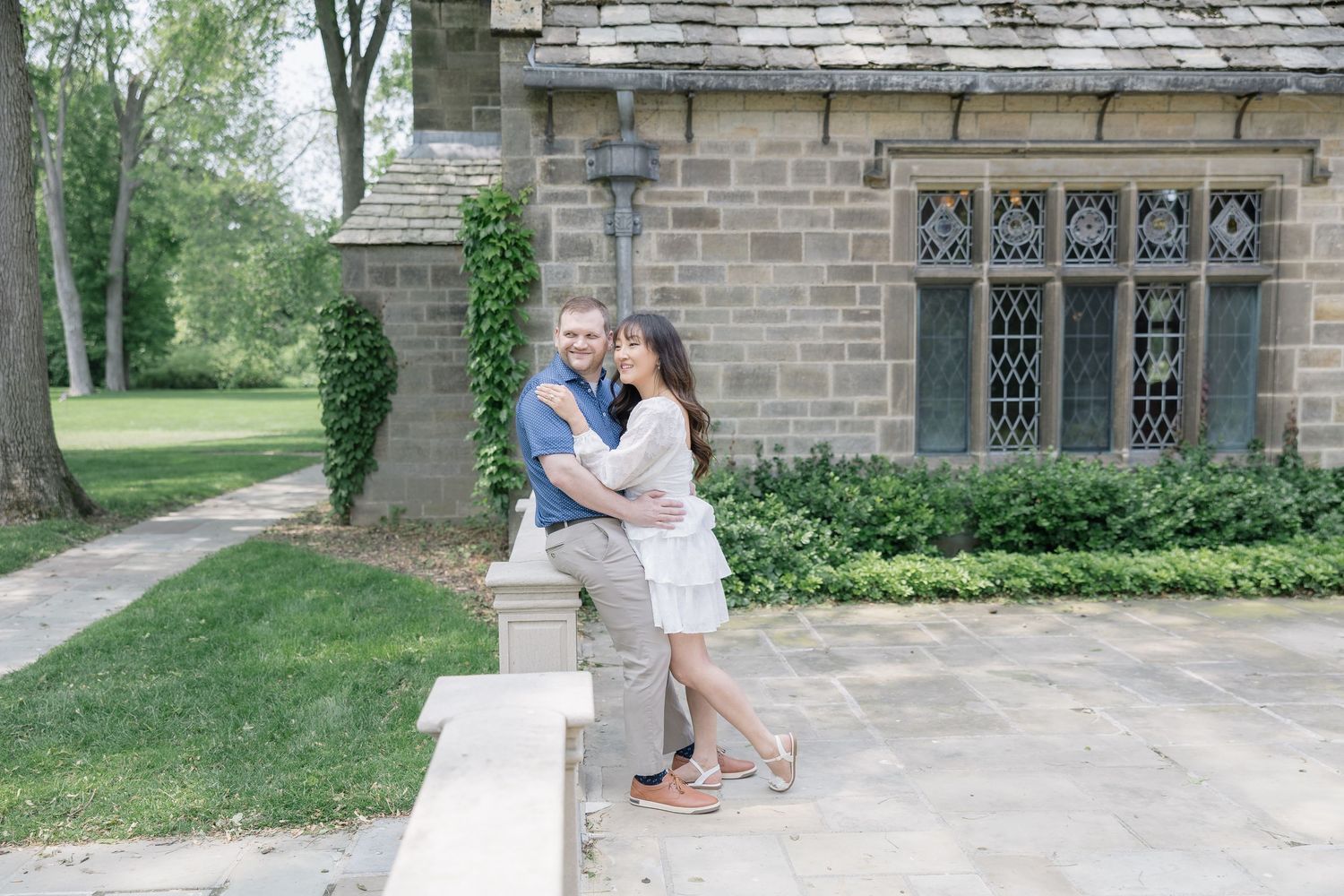 A couple shares intimate moments near a historic stone building during their engagement session.