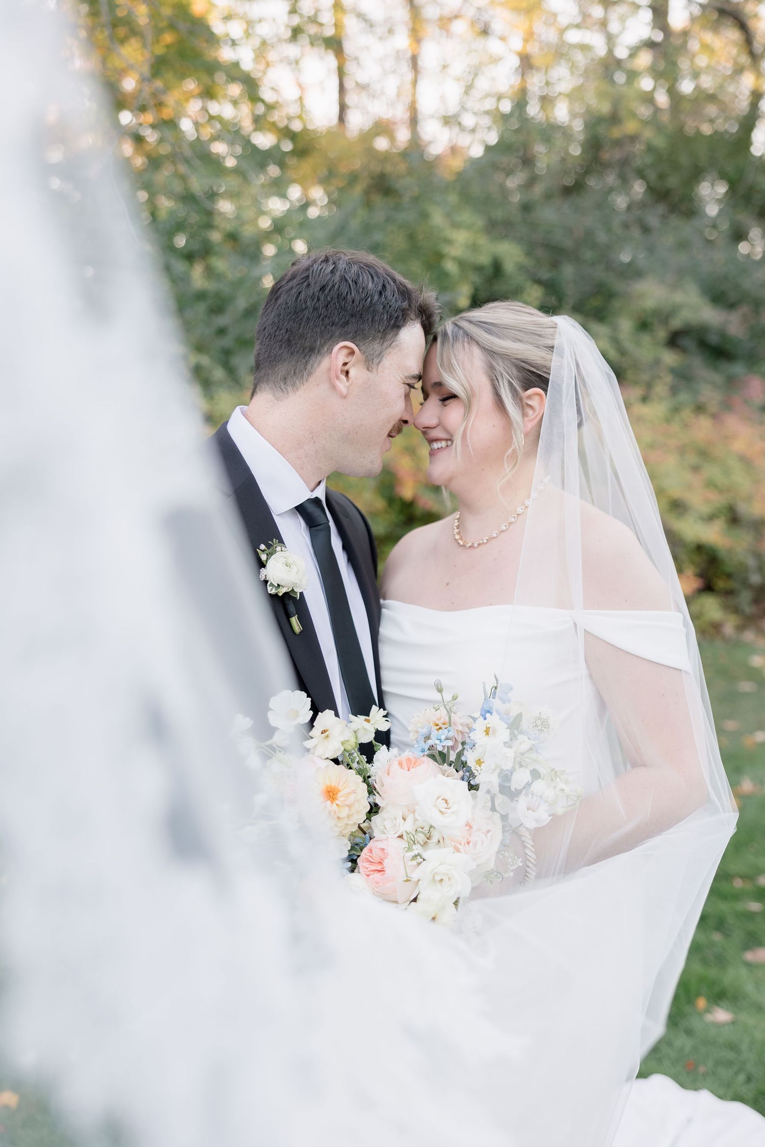 A romantic wedding portrait with a delicate veil and pastel flower bouquet.