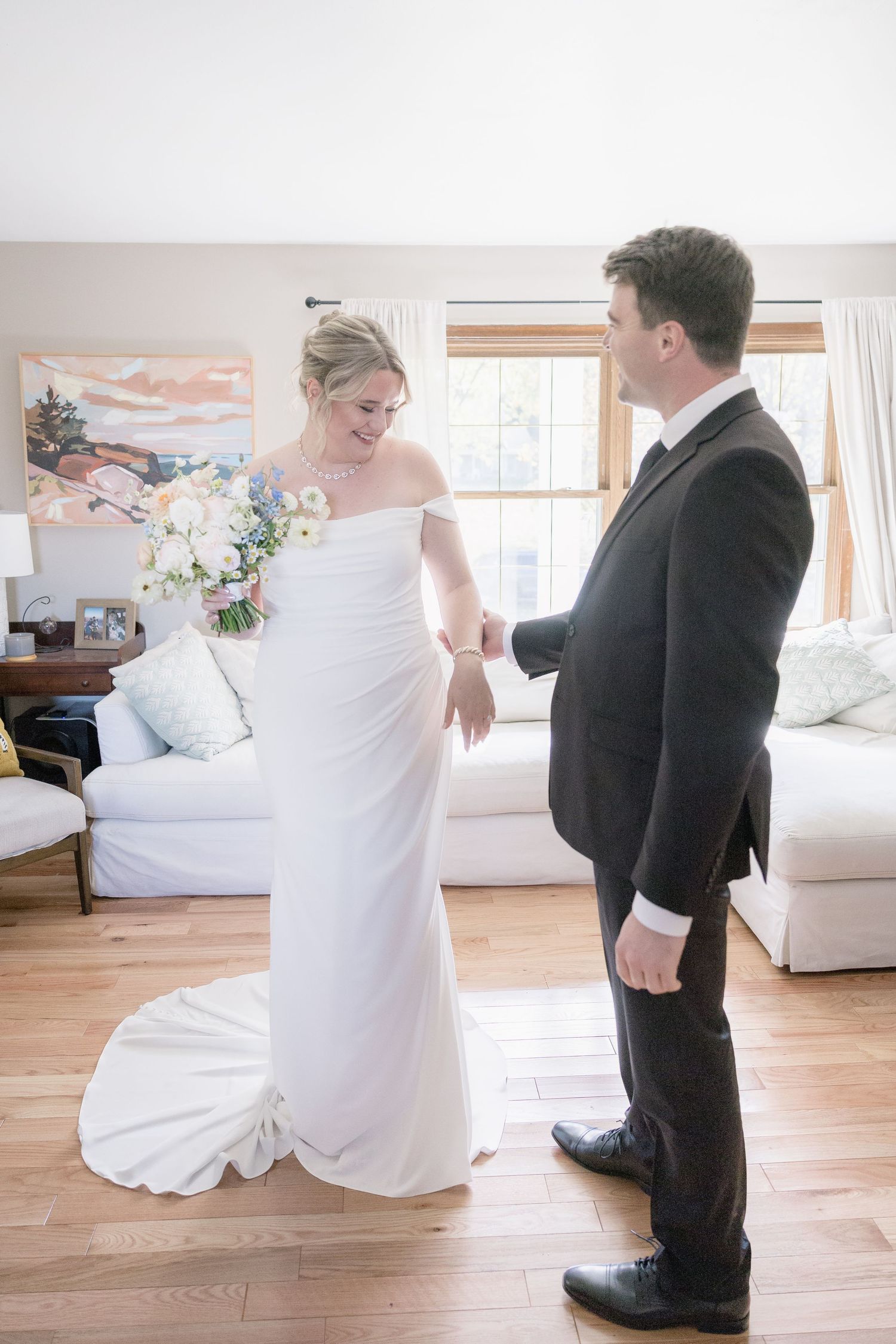 A candid moment showing a bride in a white off-shoulder dress with her groom in a classic black suit.