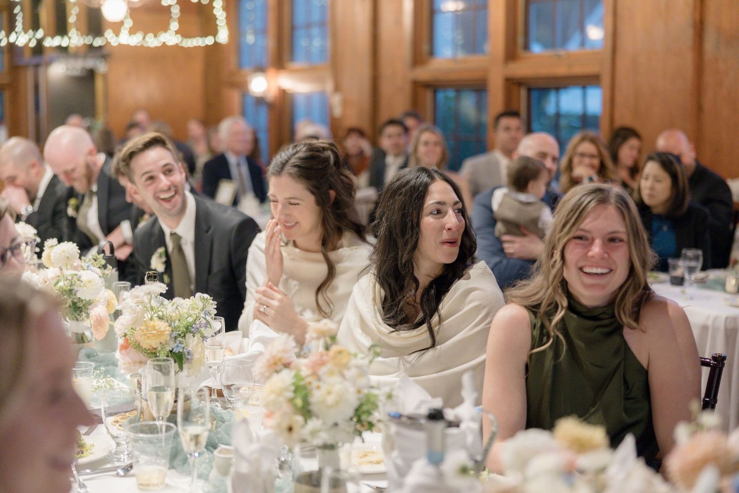 Wedding guests enjoying candid moments at reception with elegant floral centerpieces.