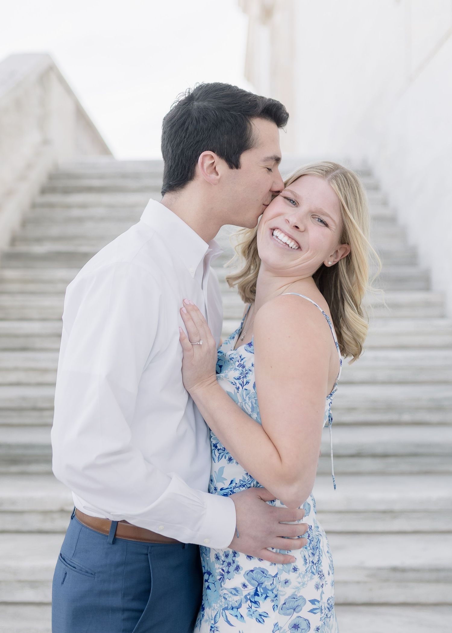 An intimate moment captured between a couple on a grand white staircase.