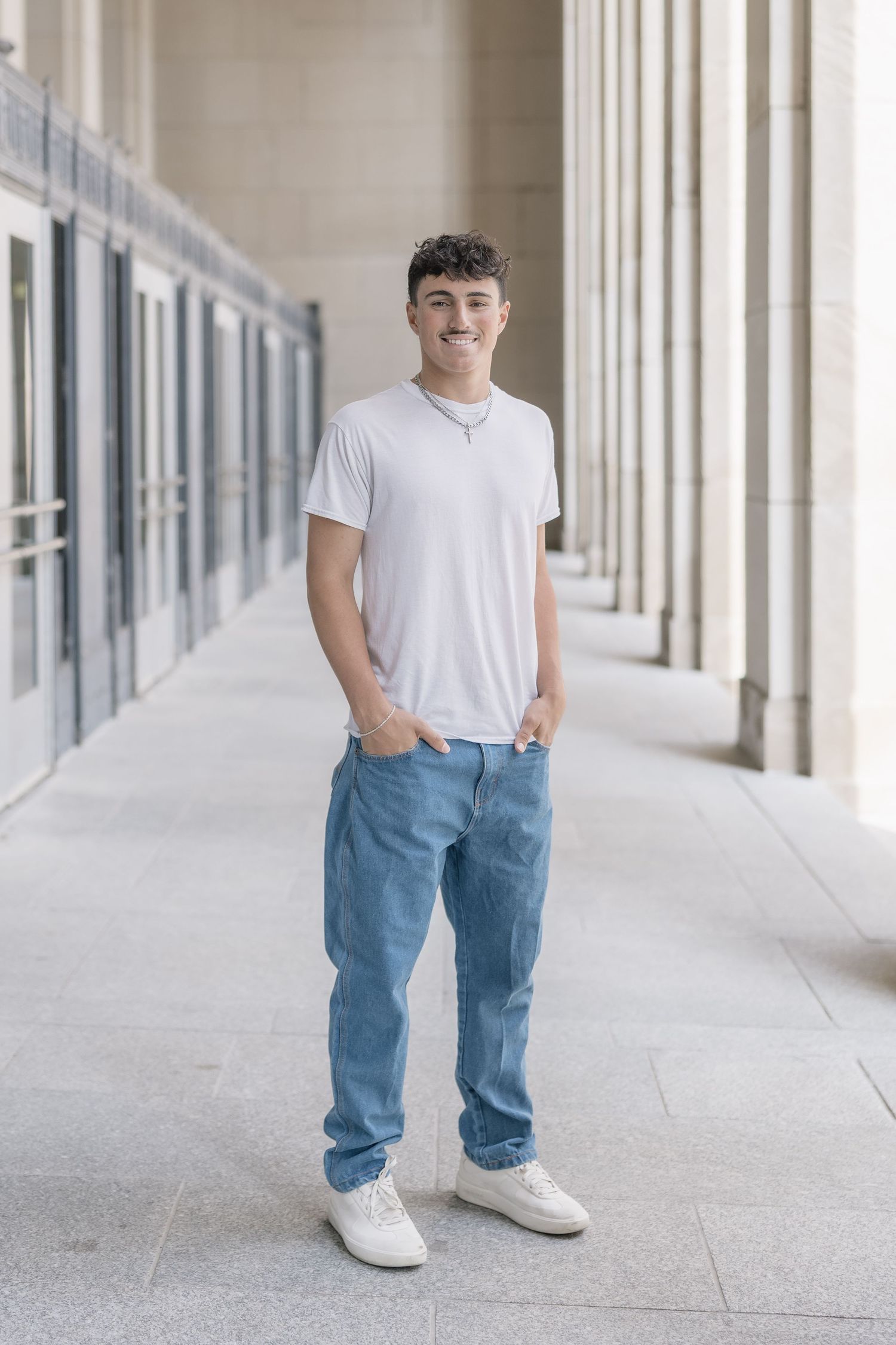 A series of five connected photos showing someone posing in a white t-shirt, jeans and white sneakers in a hallway.