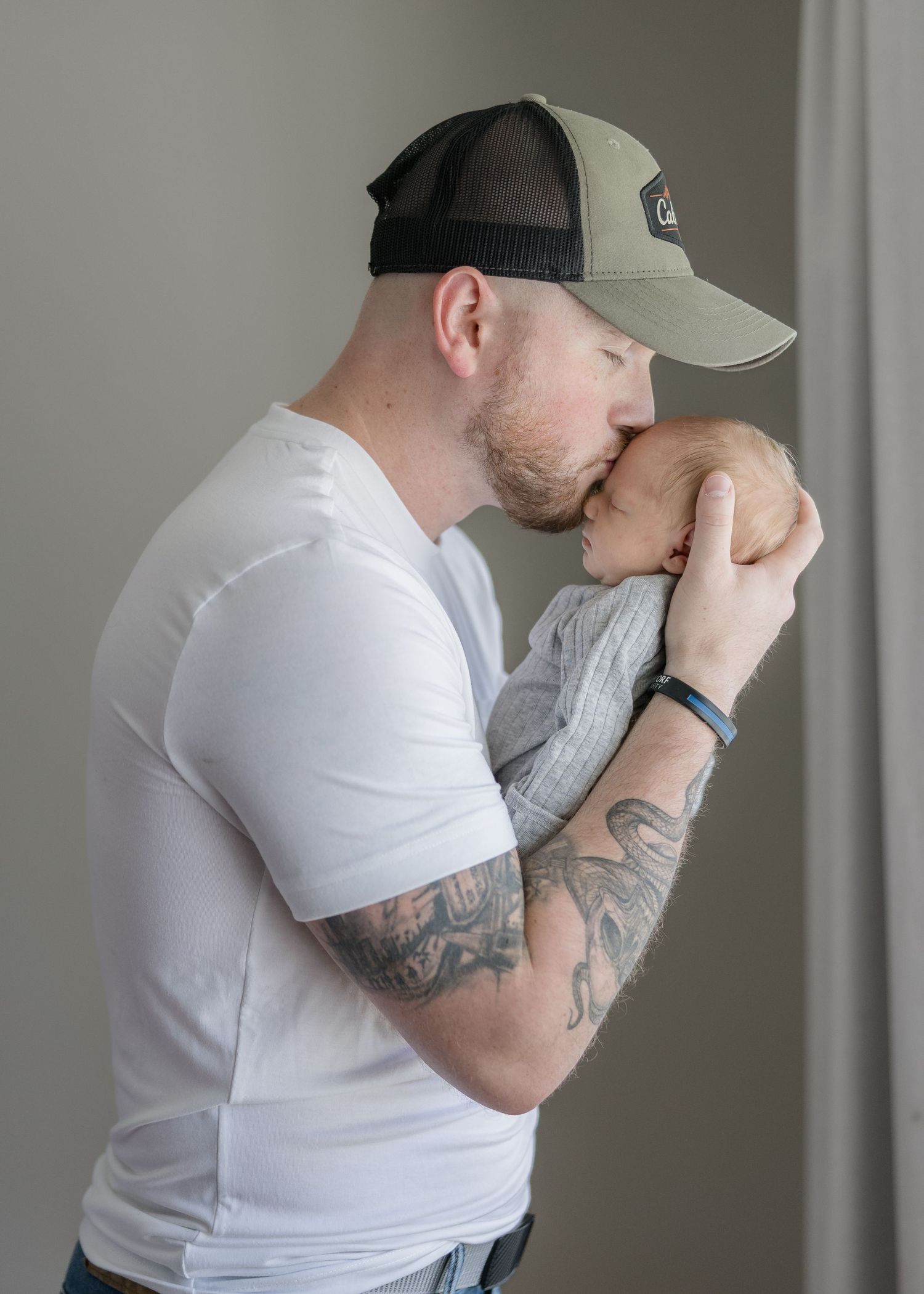 A series of photos showing someone in a white t-shirt and baseball cap covering their face with their tattooed arm.
