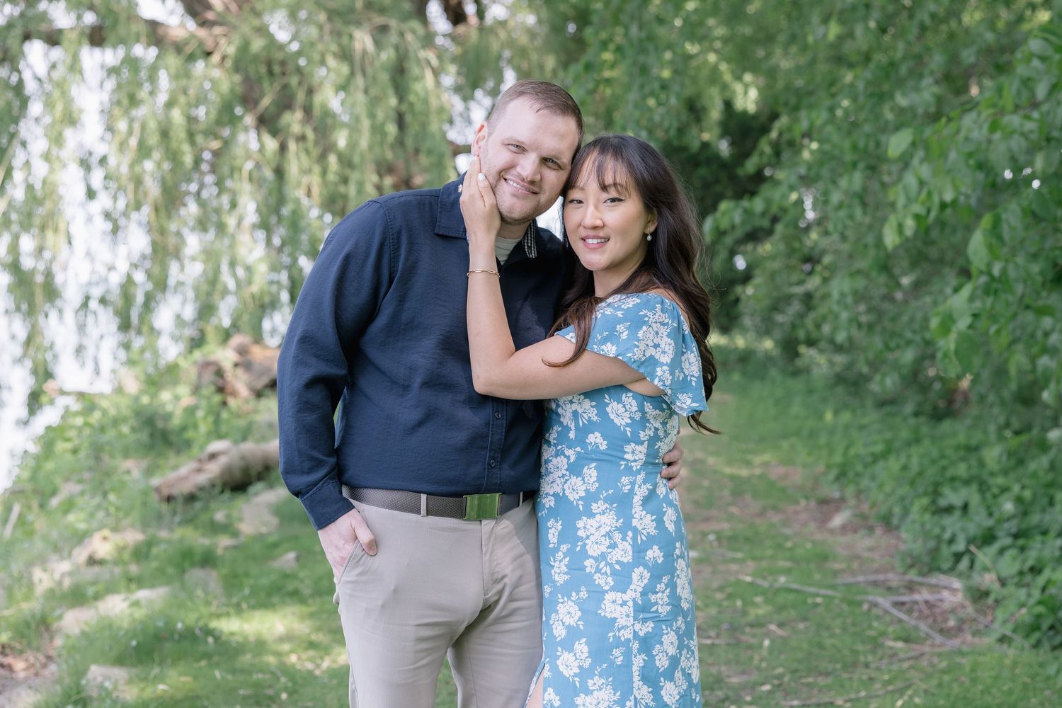Couple sharing joyful moment together under willow trees in outdoor setting.