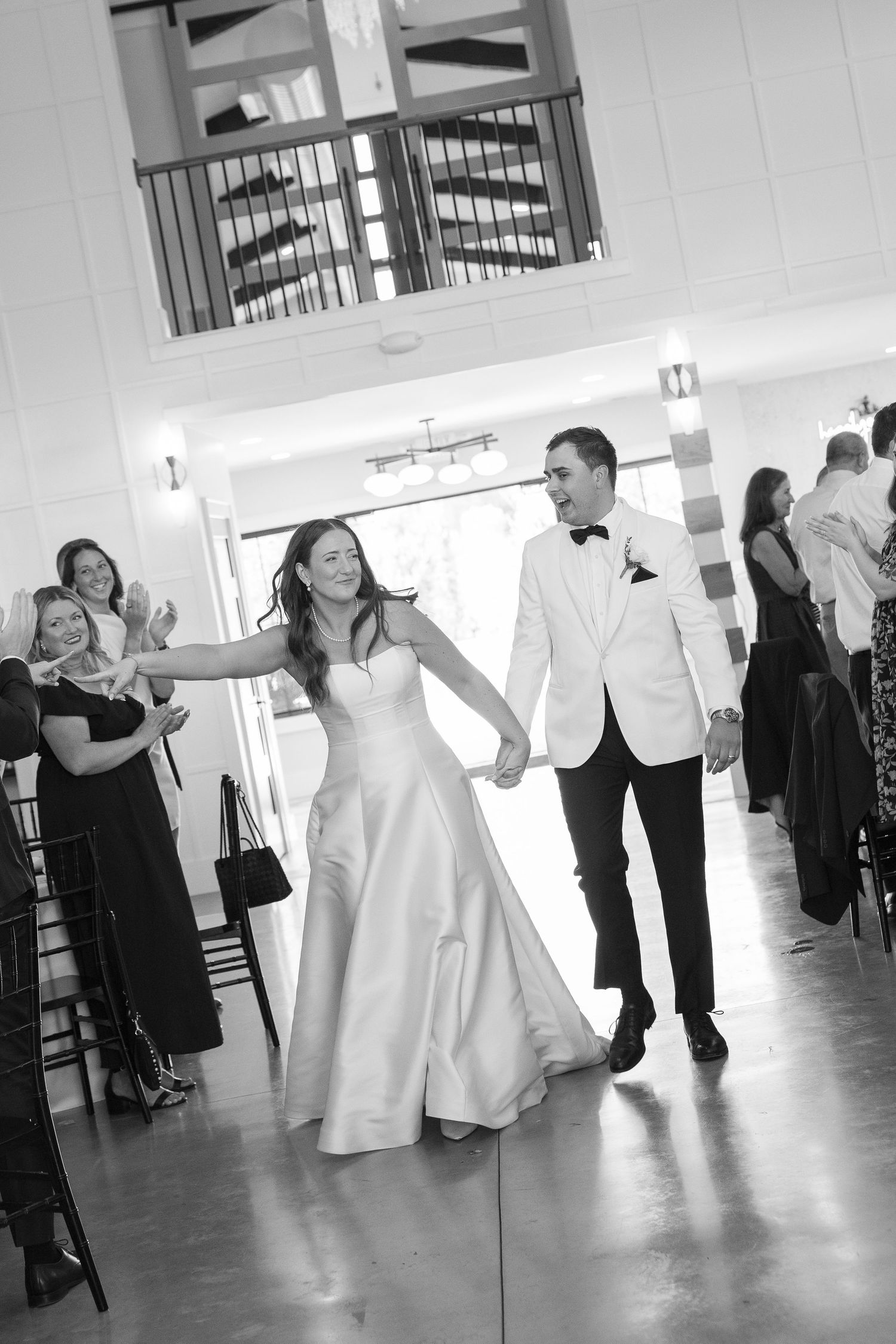 Bride and groom make grand entrance at elegant wedding reception as guests applaud.