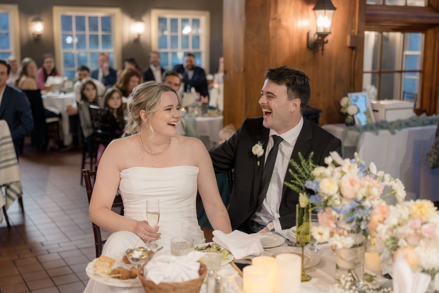 Couple sharing intimate moment at reception table decorated with soft floral arrangements and candles.