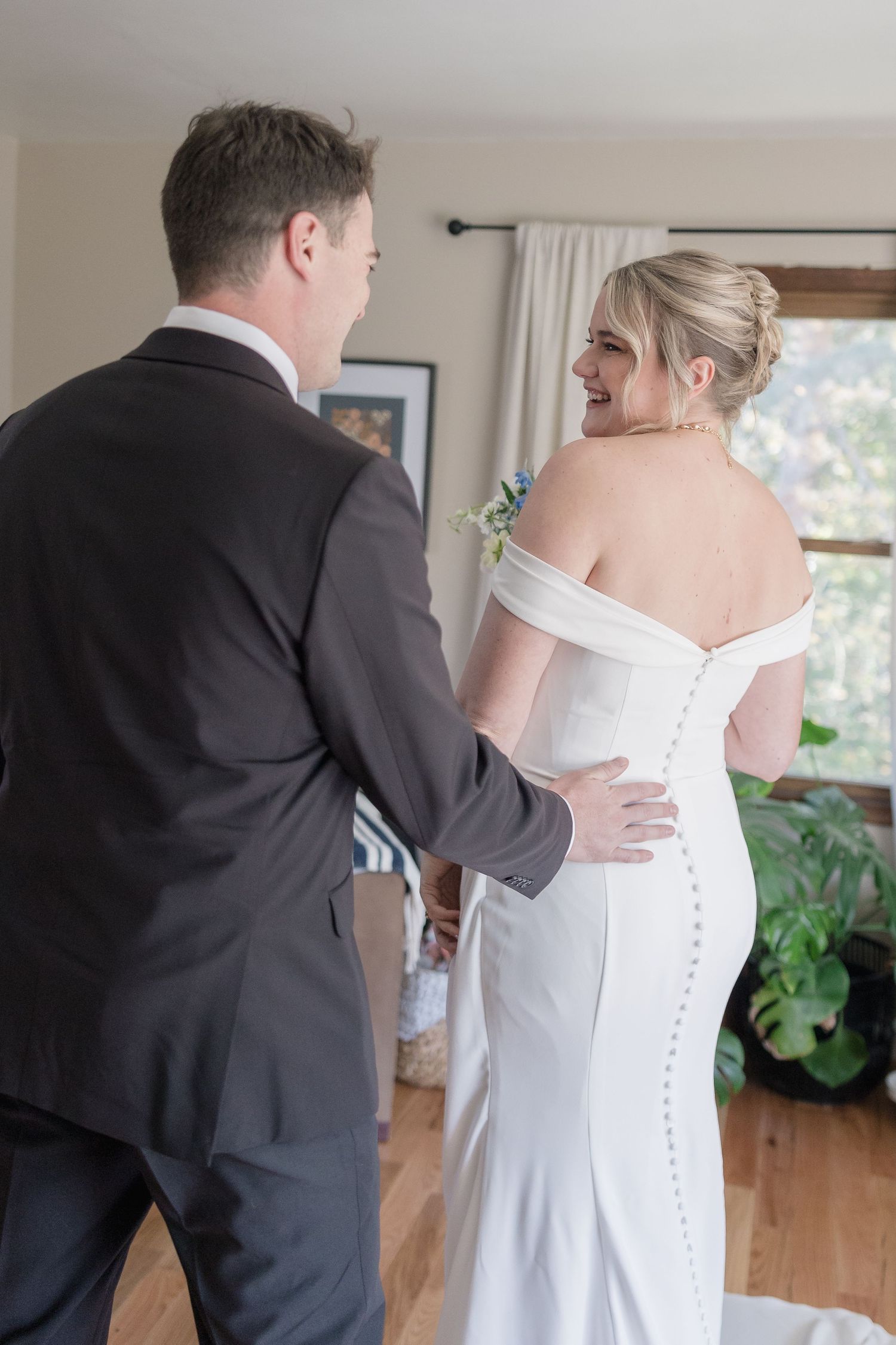 A behind-the-scenes moment showing the elegant button detail of a bride's white wedding gown.