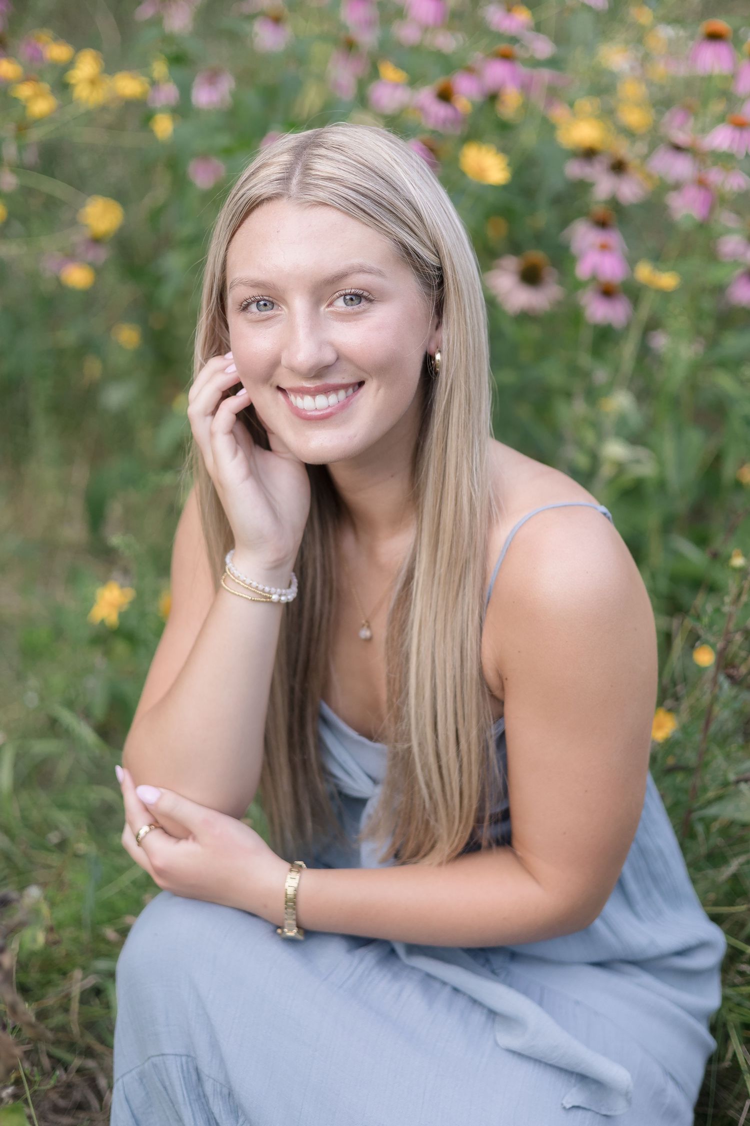 A senior portrait photoshoot in a wildflower meadow with a light blue dress against colorful summer blooms.