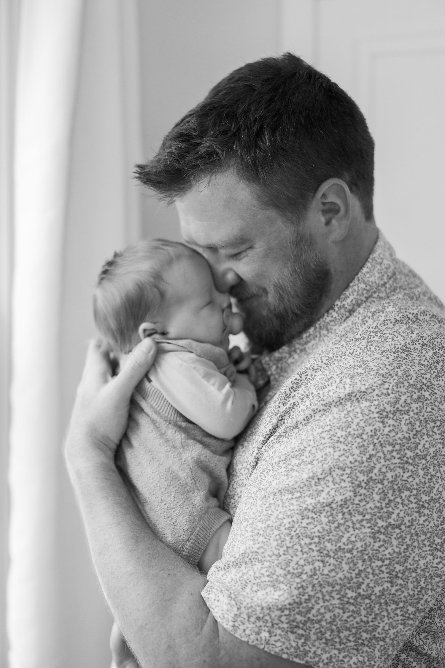 Black and white photo series showing tender moments between parent and newborn baby in soft natural light.