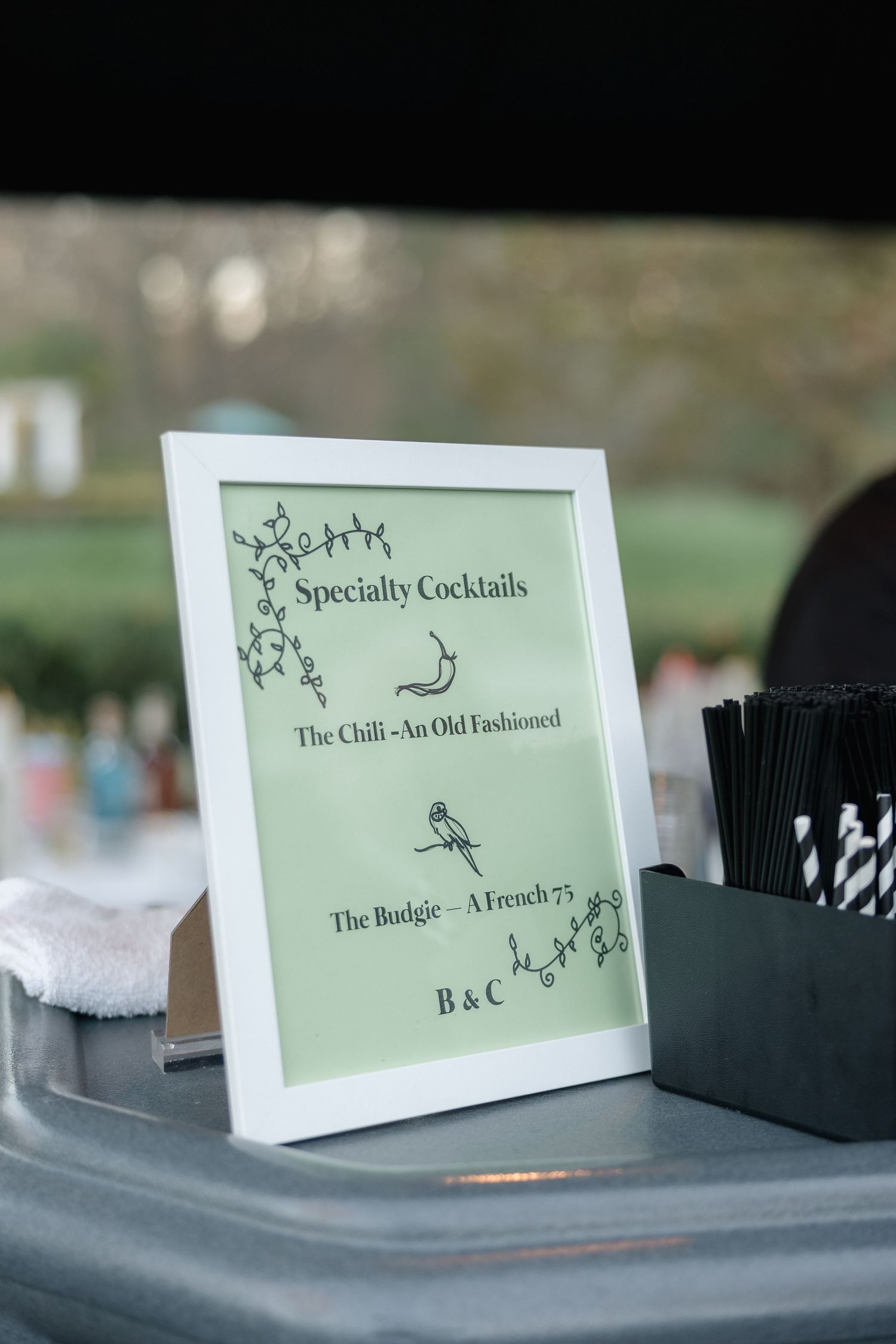 Wedding reception specialty cocktail menu in a white frame with decorative floral design.
