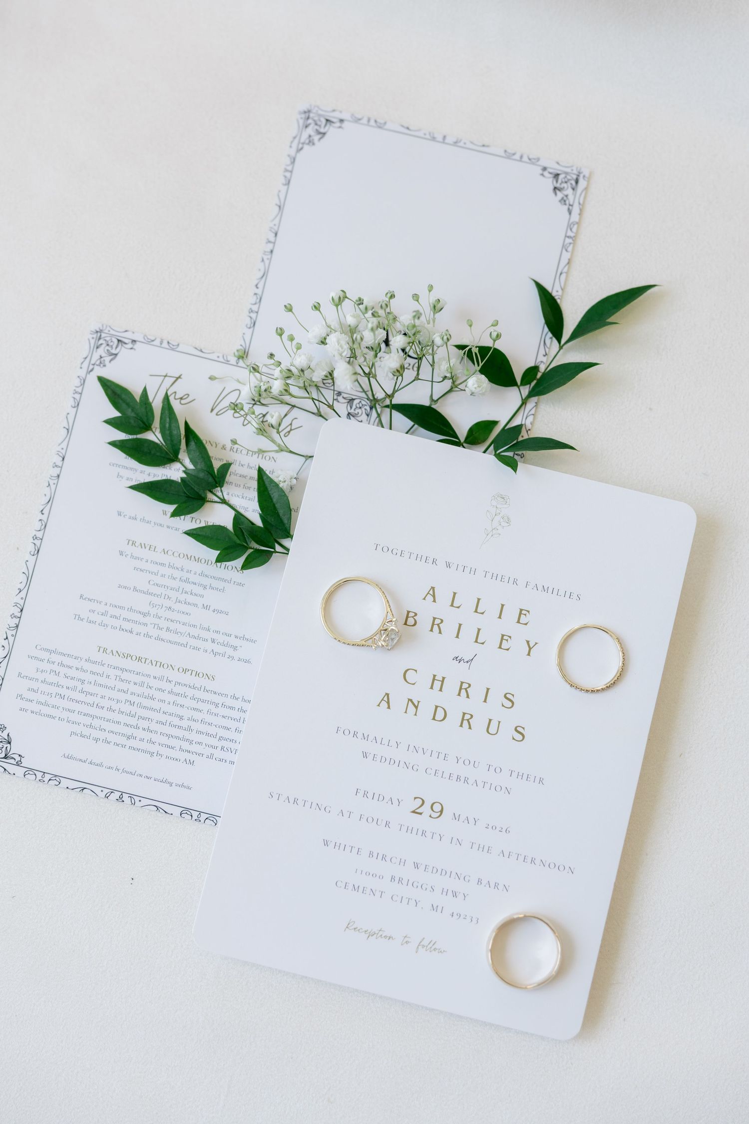 Wedding invitation suite for Allie Briley and Chris Andrus with gold rings and fresh greenery accents.