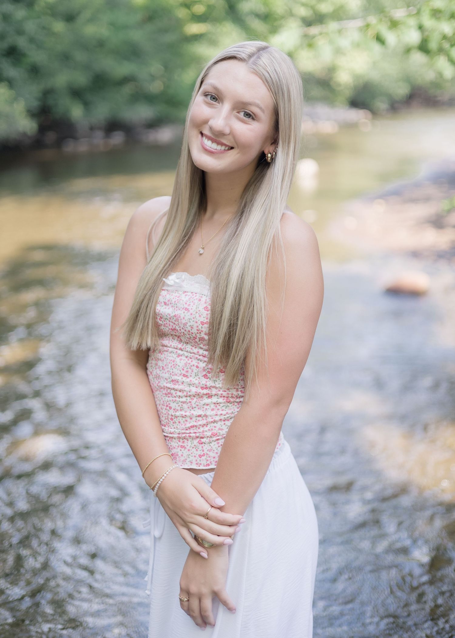 A person in a sparkly pink top poses by a stream in multiple candid shots.