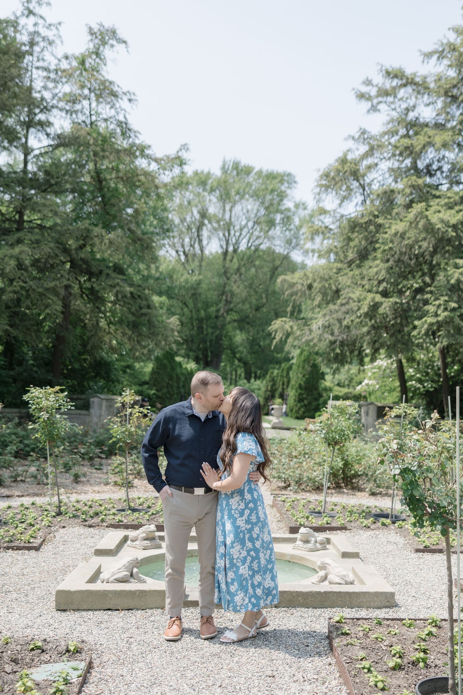 A couple takes a romantic stroll through a beautiful garden pathway surrounded by greenery.