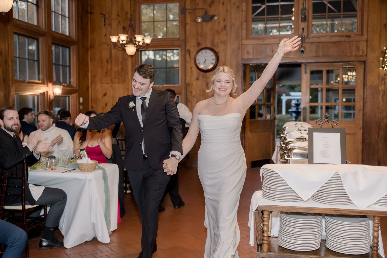 Newlyweds celebrate with joy while exiting their wooden barn wedding reception venue.