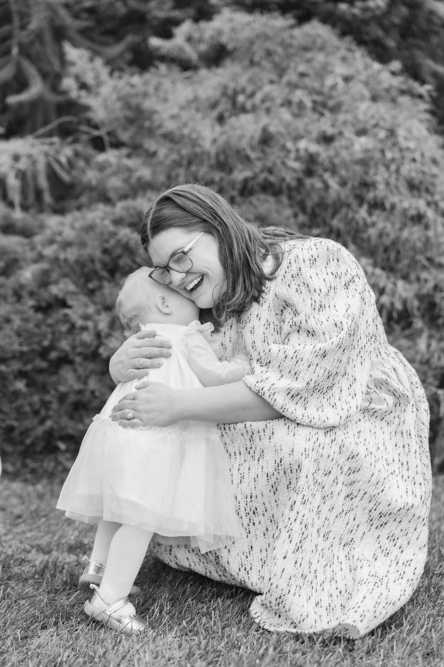 A tender black and white photo series showing a parent in a lace dress sharing sweet moments with a baby in white.