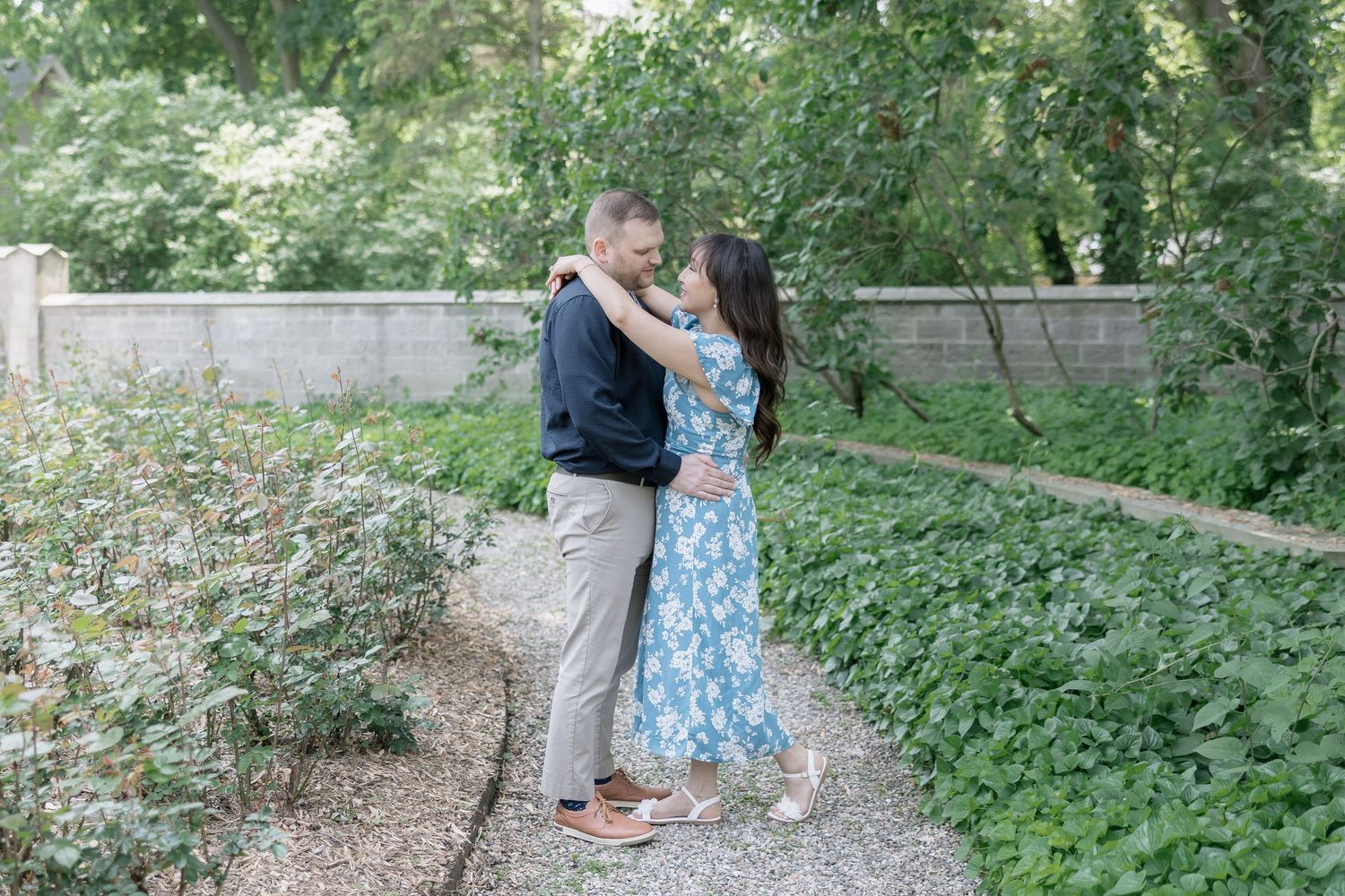 Two people enjoying a romantic moment on a stone path surrounded by greenery.