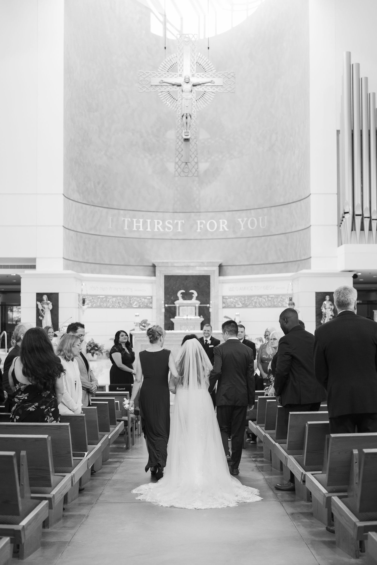 Wedding ceremony inside a traditional church with guests seated in wooden pews.