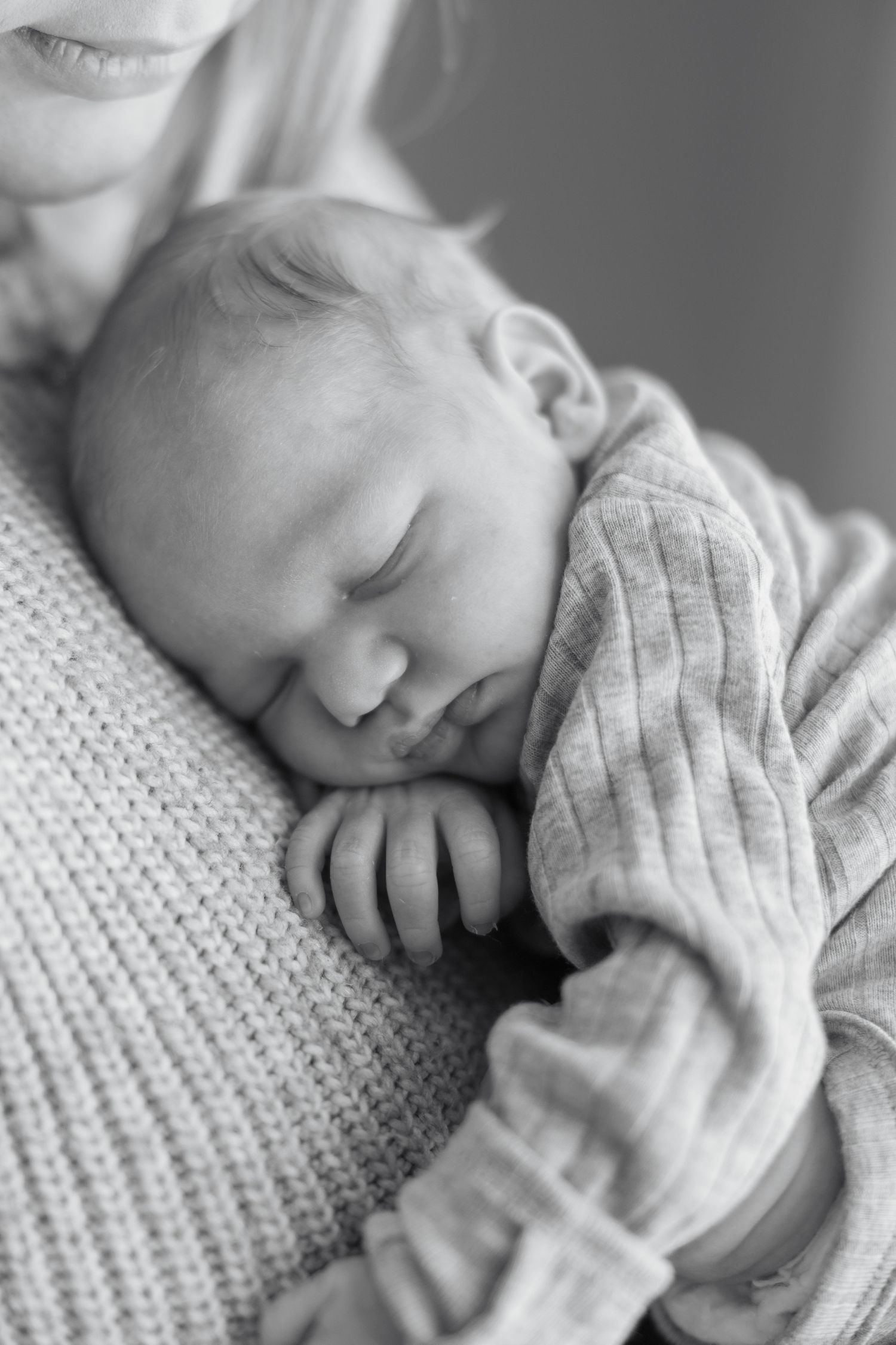A peaceful black and white photo series showing a sleeping newborn baby wrapped in a soft knit blanket.