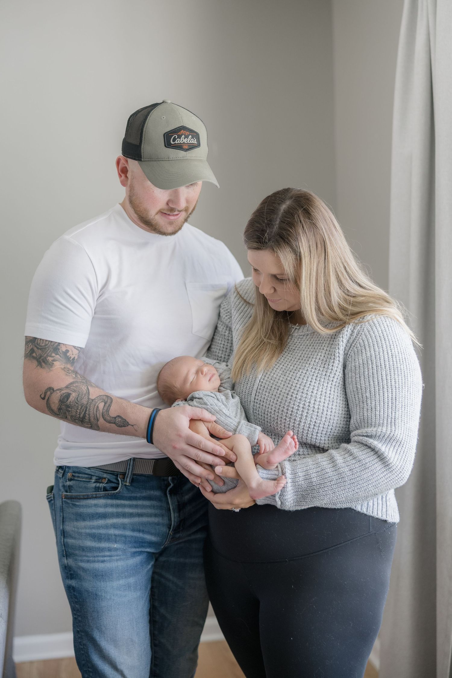 Parents in casual attire share tender moments with their newborn baby in a series of intimate indoor portraits.
