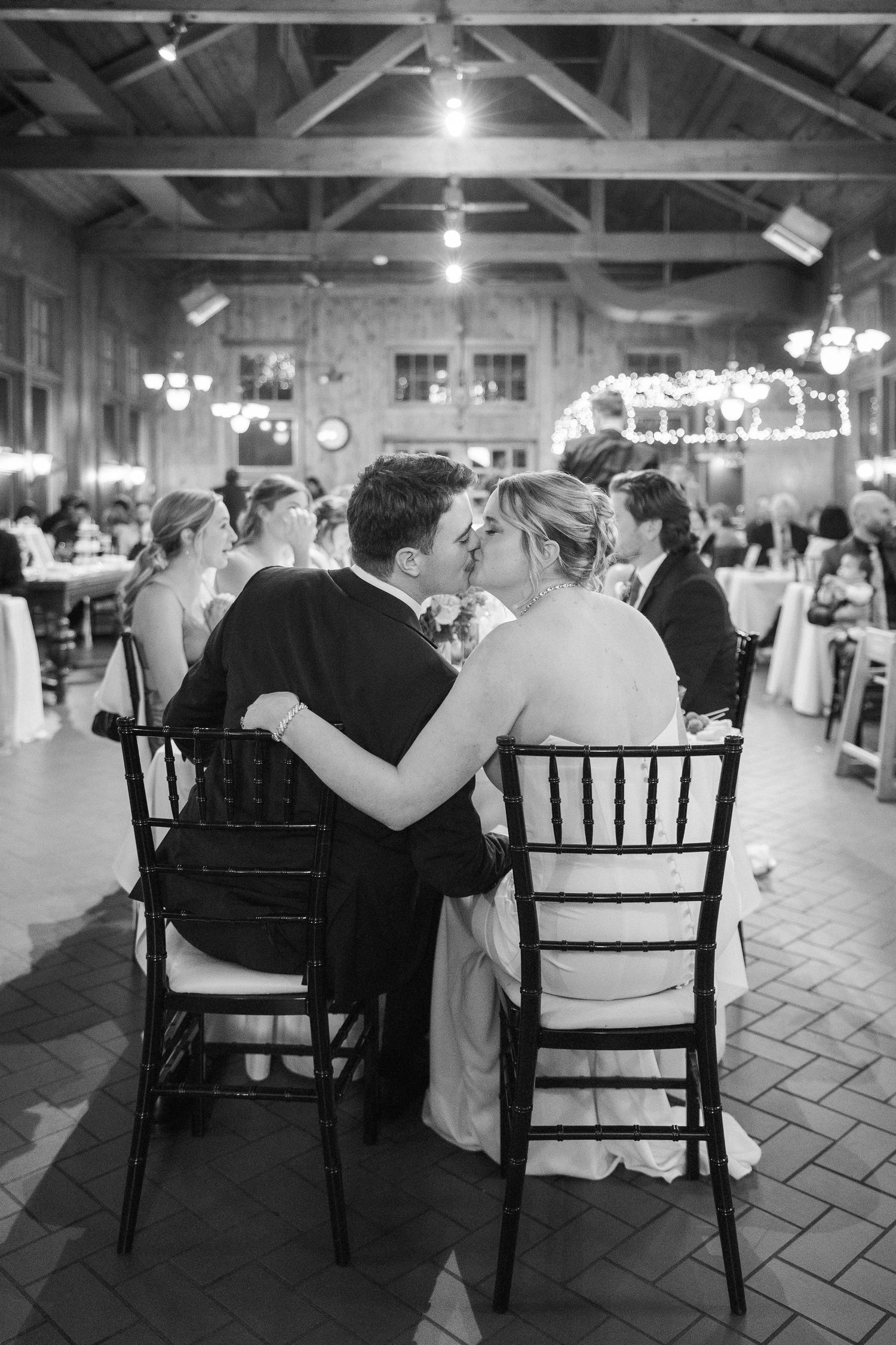 Black and white romantic moment between couple at reception venue with exposed beam ceiling.