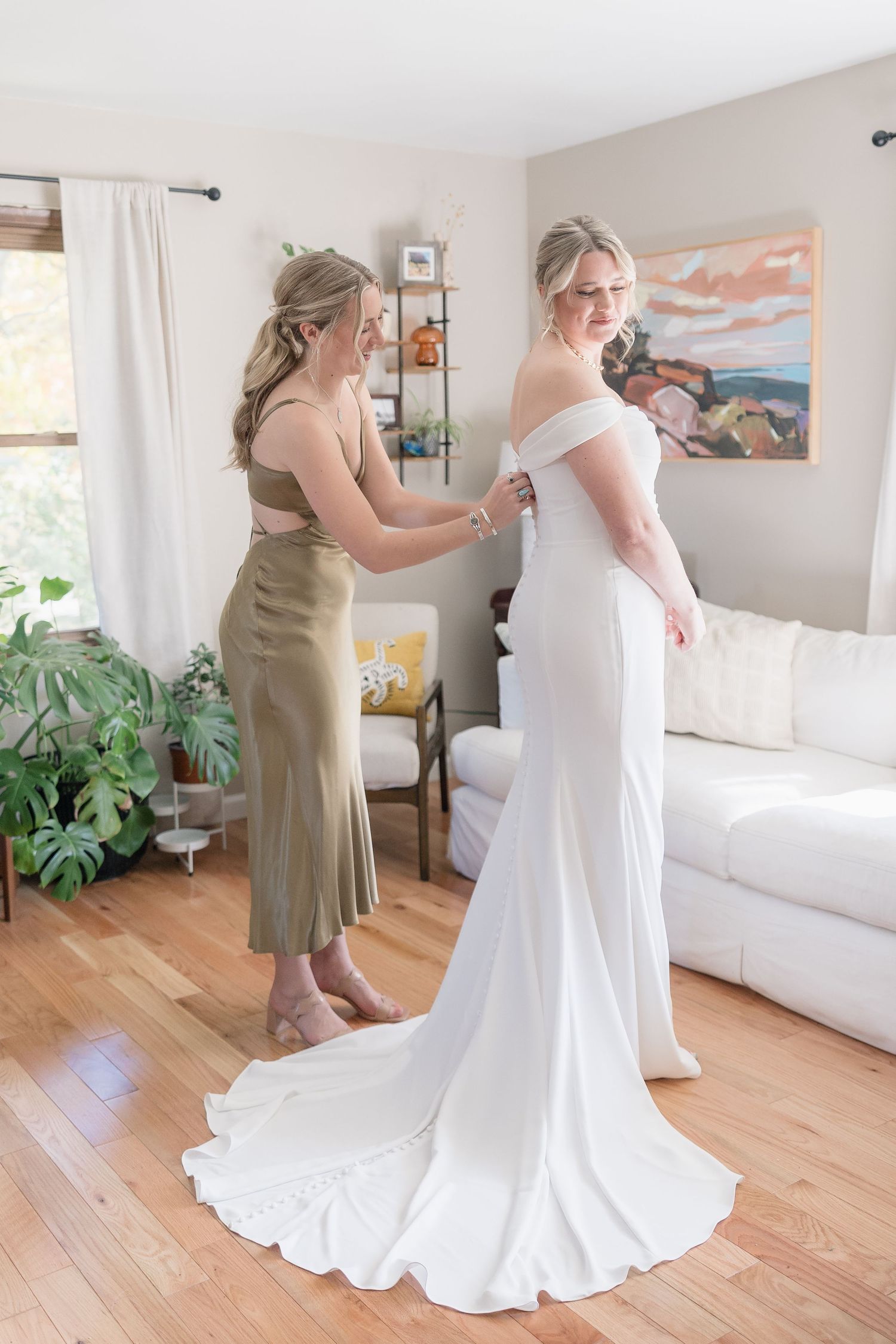 An elegant white wedding gown with a flowing train in a modern living room setting.