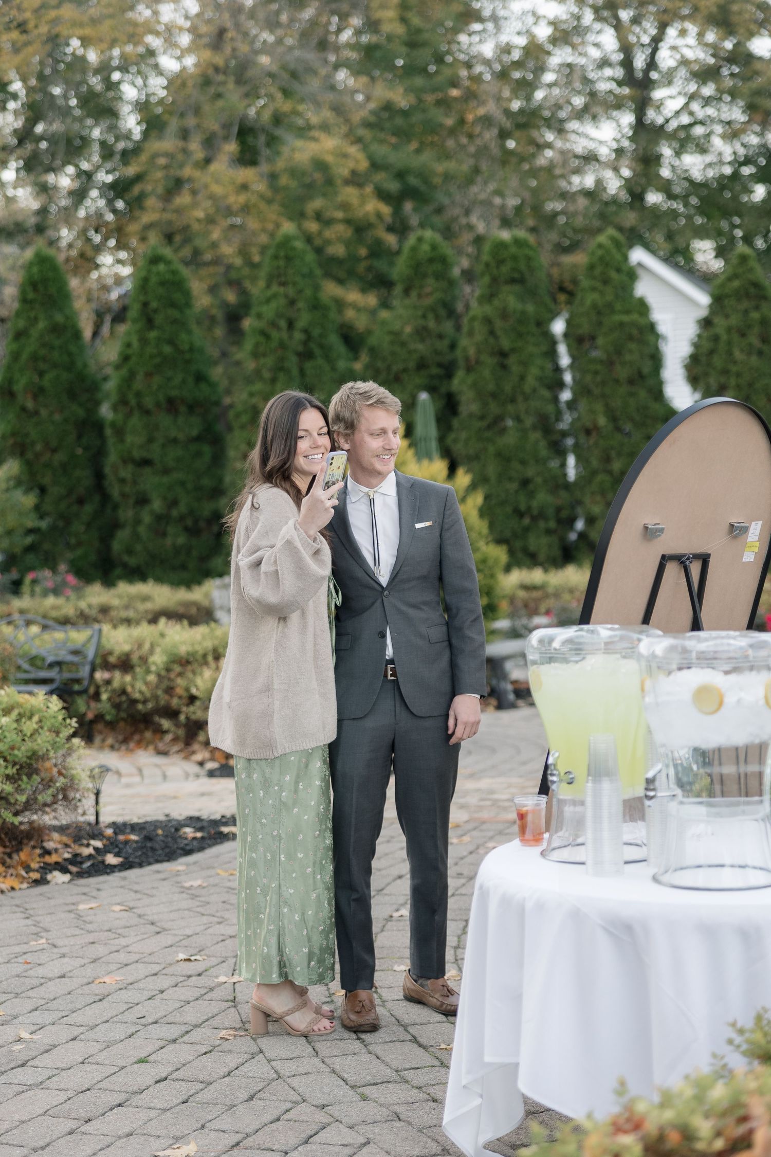 Wedding guests enjoying drinks at an outdoor cocktail table during fall season.