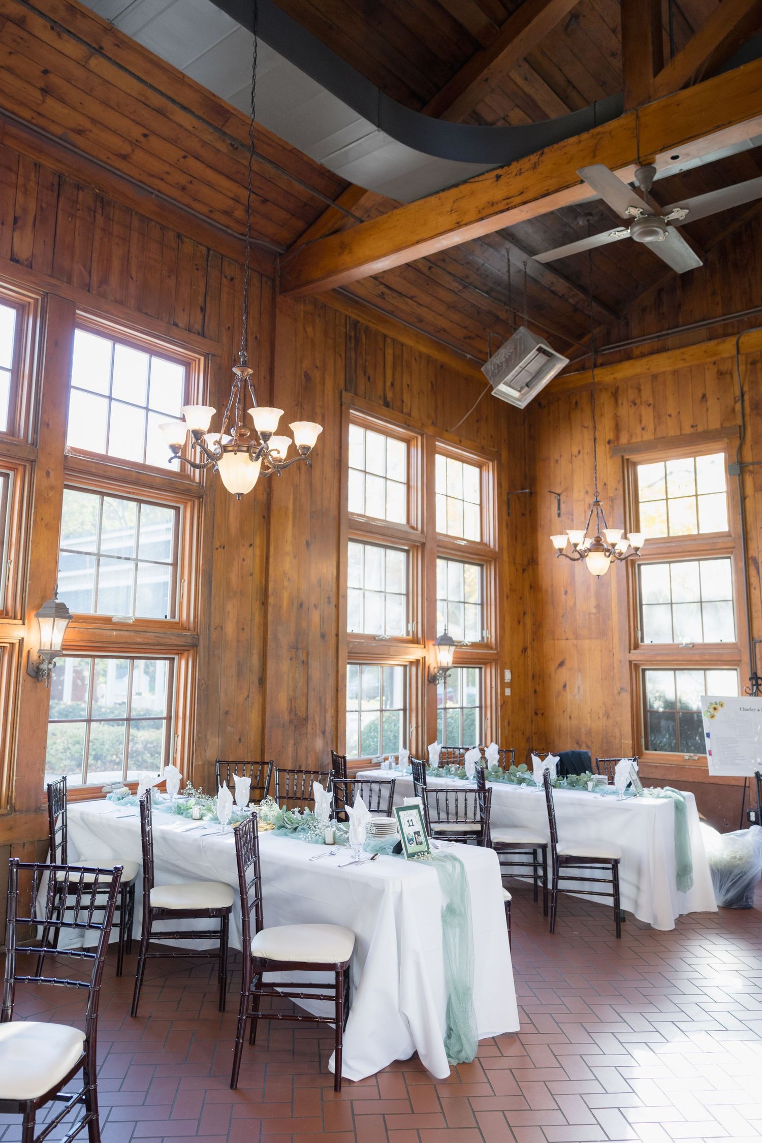 Rustic wooden reception hall with high ceilings and elegant table settings for wedding celebration.