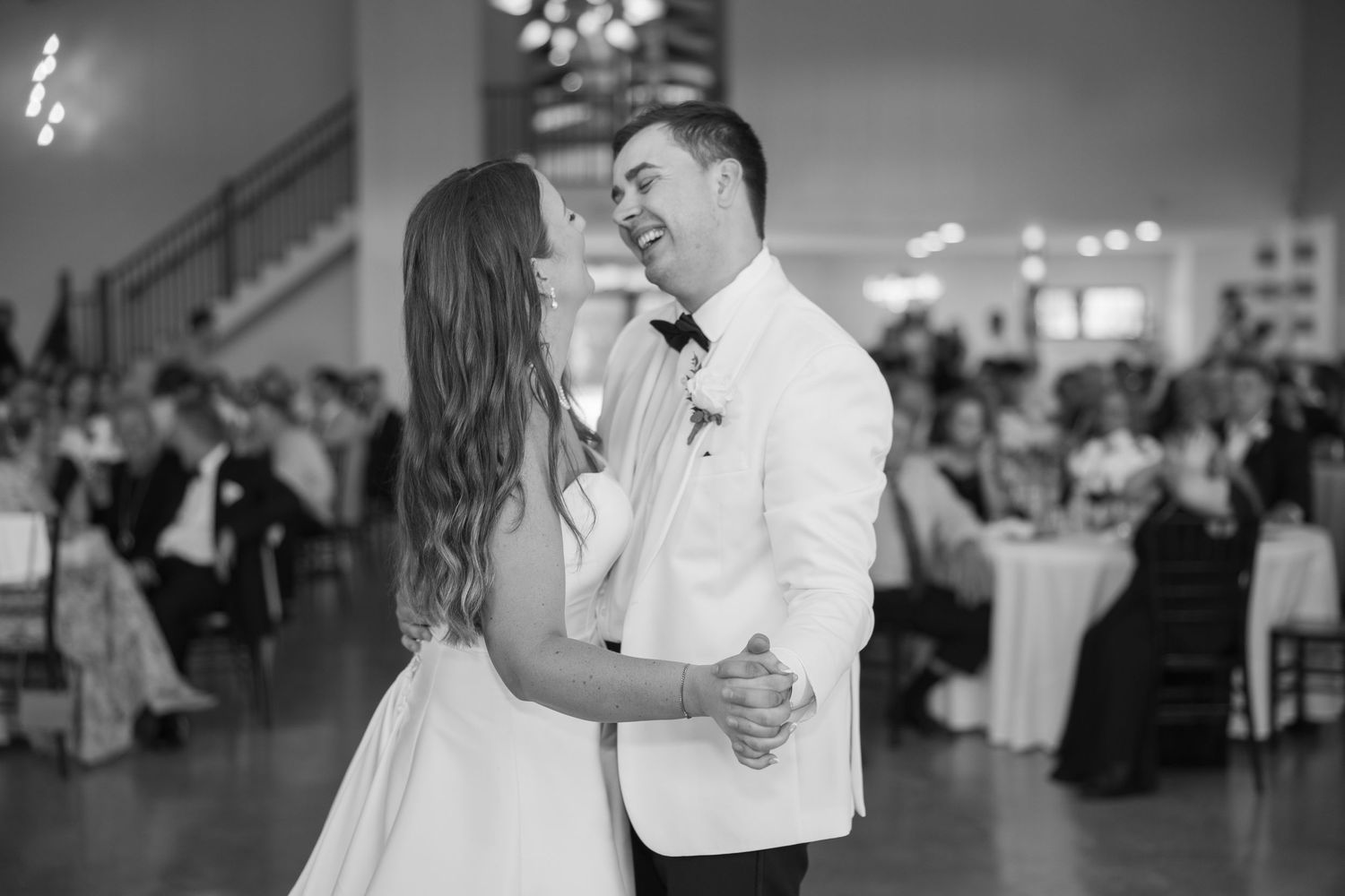 Bride and groom share romantic first dance at elegant wedding reception in black and white.