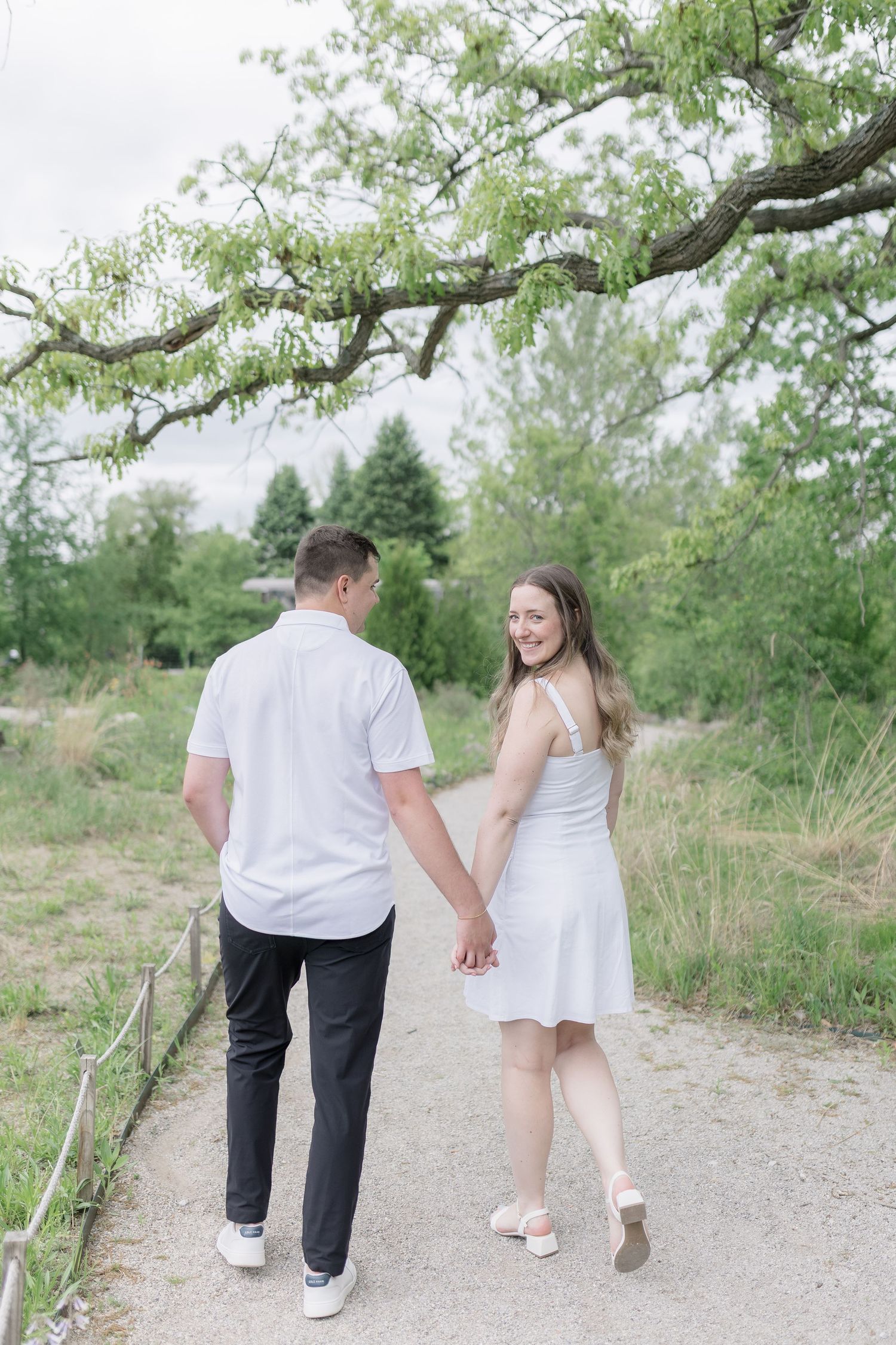 Casual engagement photos of couple walking along natural outdoor path.