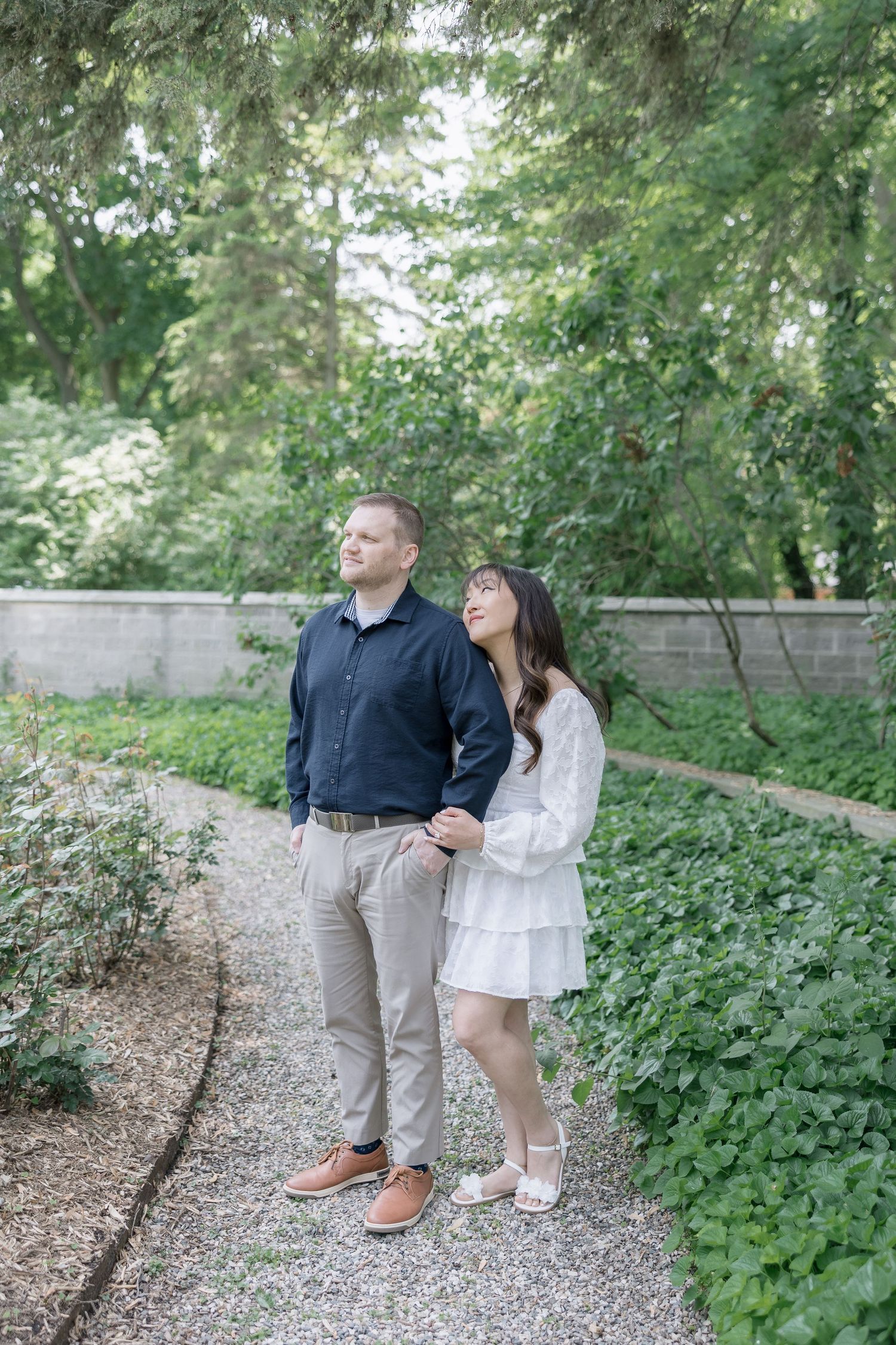 Couple walking together on a garden path surrounded by lush green foliage.