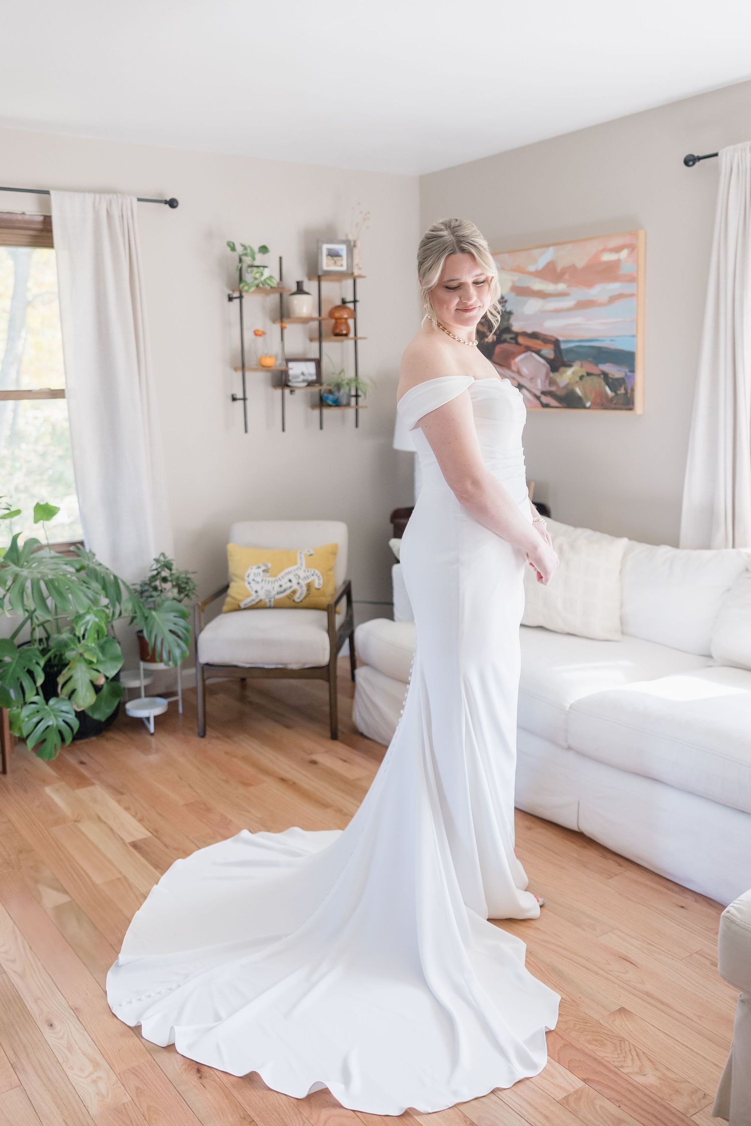 A stunning off-shoulder wedding dress with a dramatic train in a bright, contemporary space.