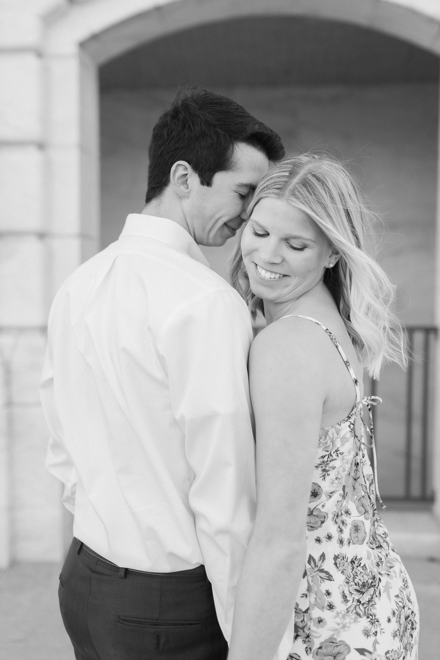 A romantic black and white portrait of a couple sharing an intimate moment together as they smile and embrace.