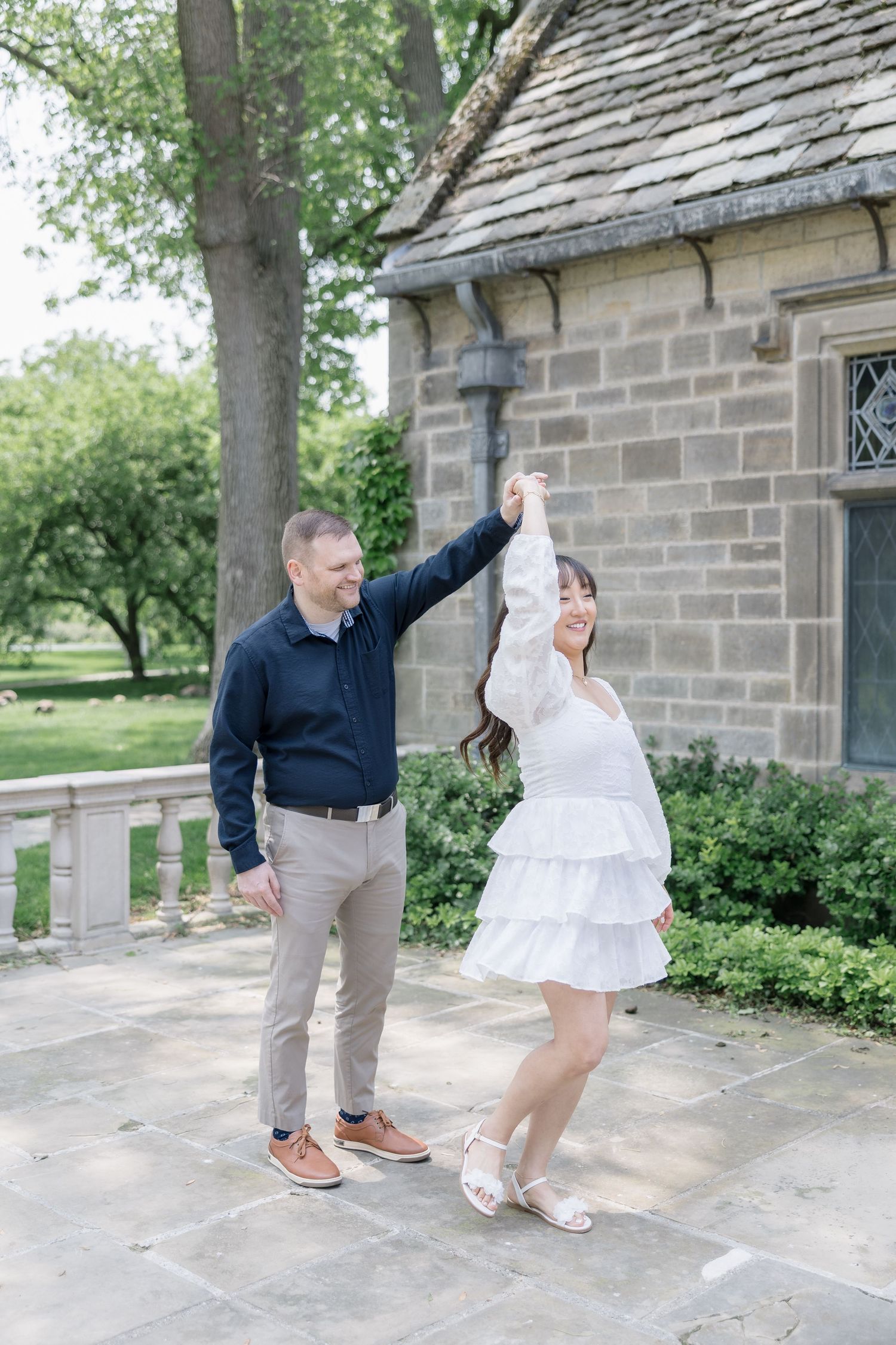 A couple dances together on a stone patio next to a brick building on a summer day.