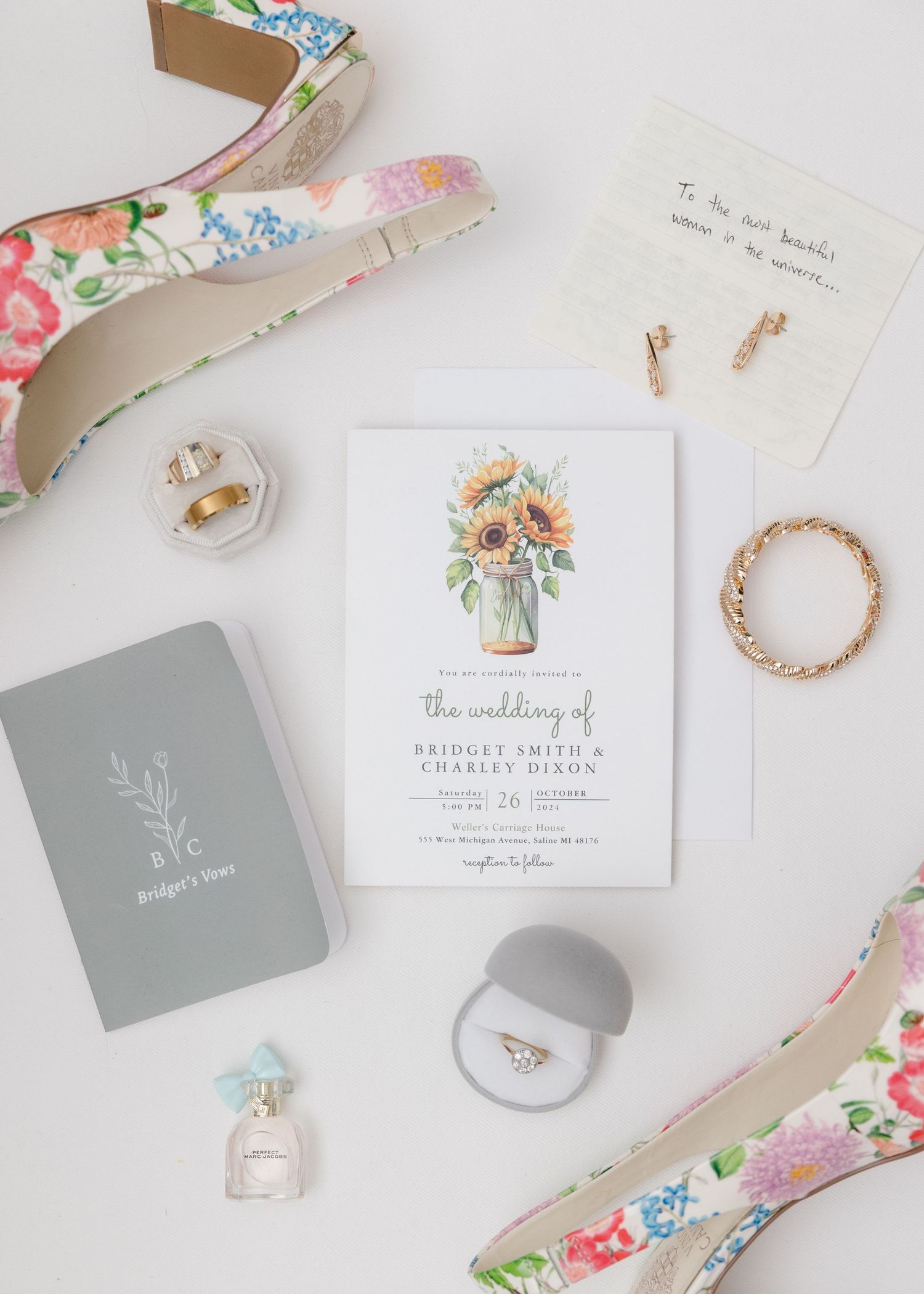 Wedding invitation and accessories including floral heels, jewelry, and perfume arranged on white background.