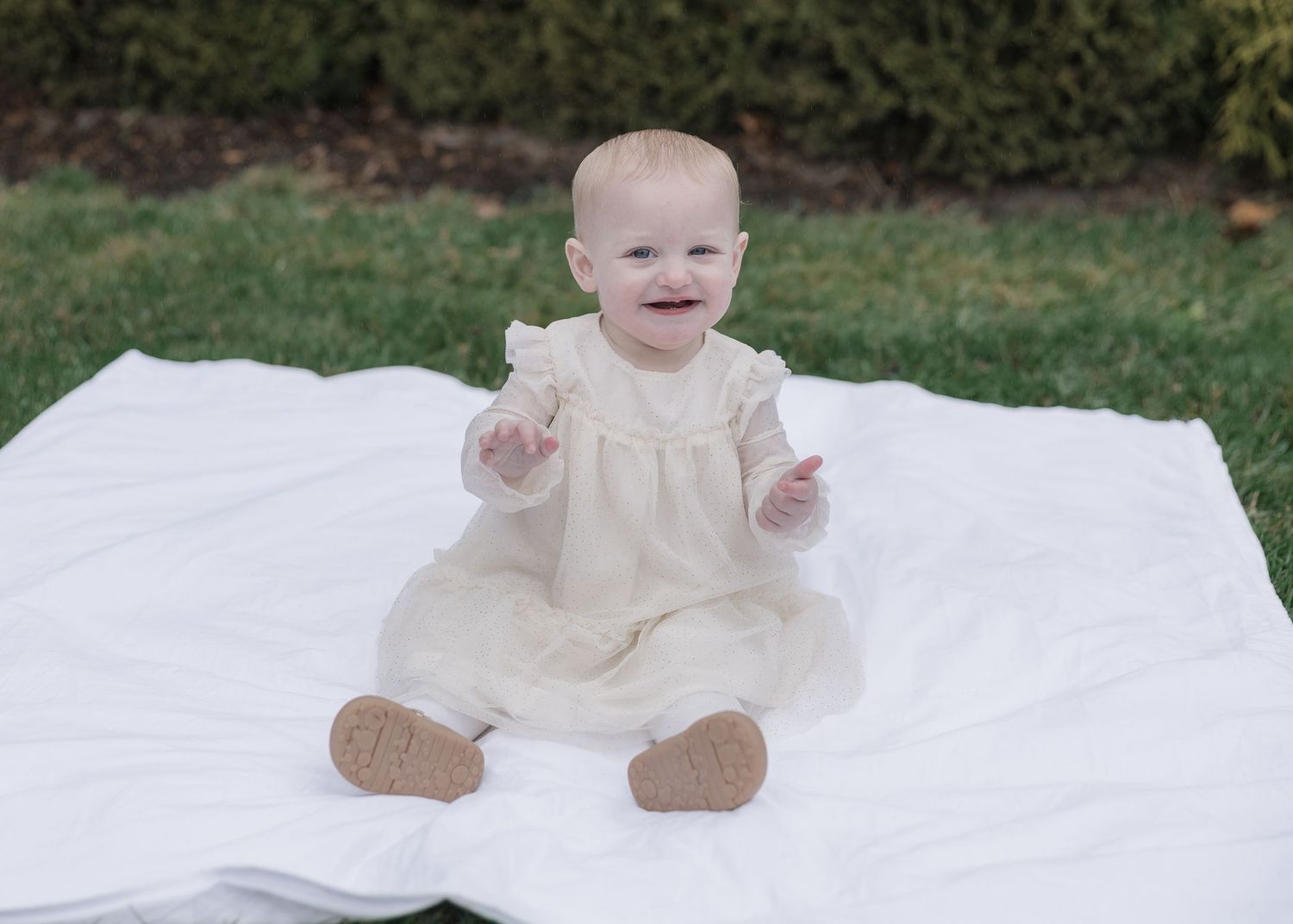 A series of seven milestone photos showing a baby's growth progression on a white blanket over time.