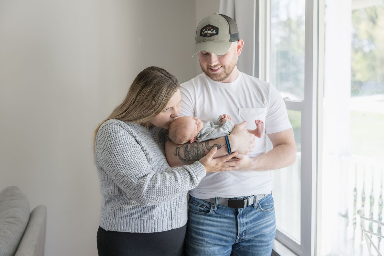 A tender family moment captured in a series of intimate black and white photographs by a window.