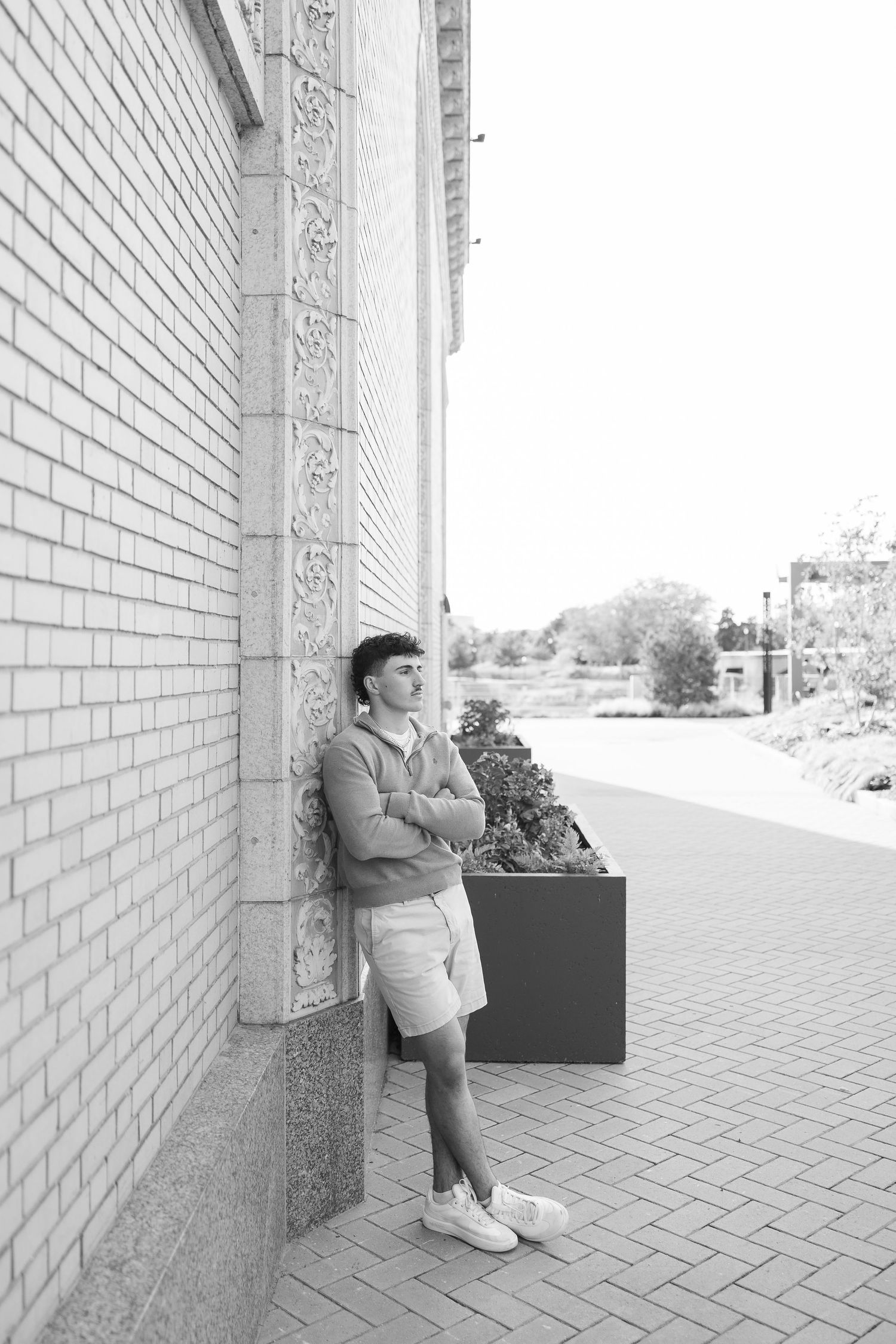 A series of four black and white photos showing someone leaning against a white brick wall in an outdoor setting.