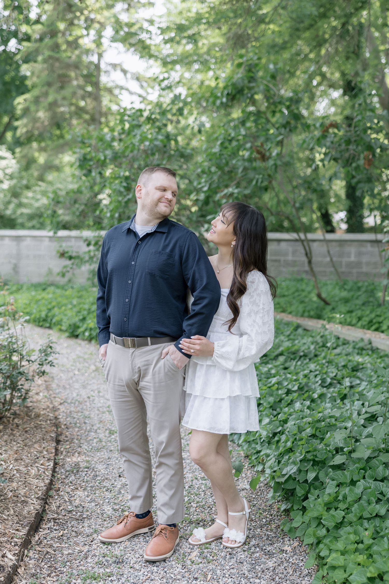 Couple sharing a romantic moment on a garden path surrounded by lush greenery.