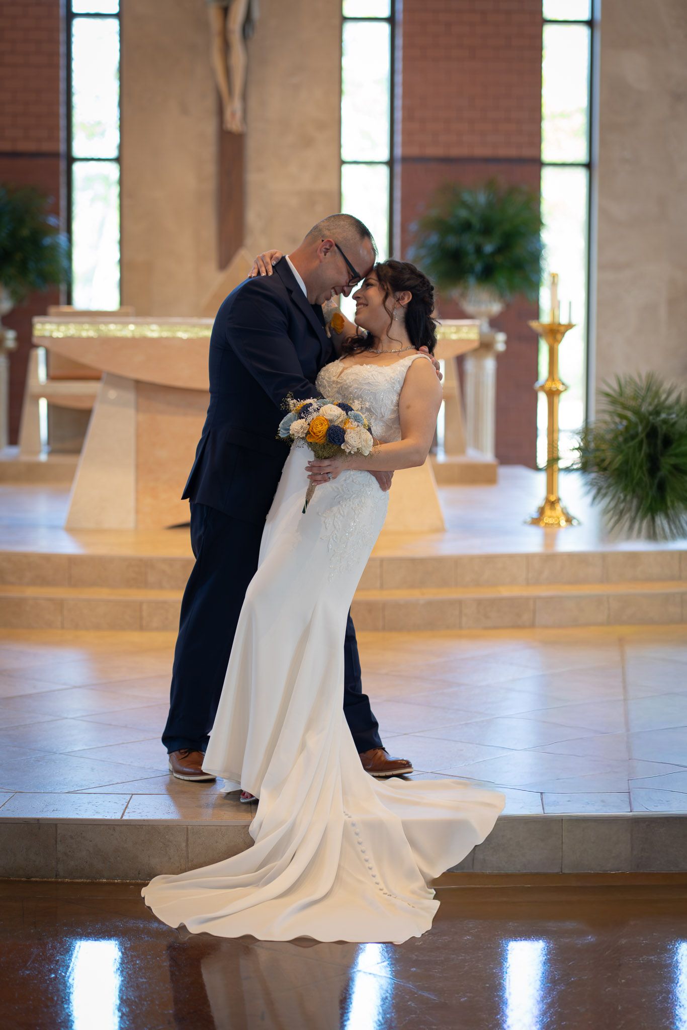Bride and groom share a romantic forehead touch at the altar of a beautiful church on their wedding day.