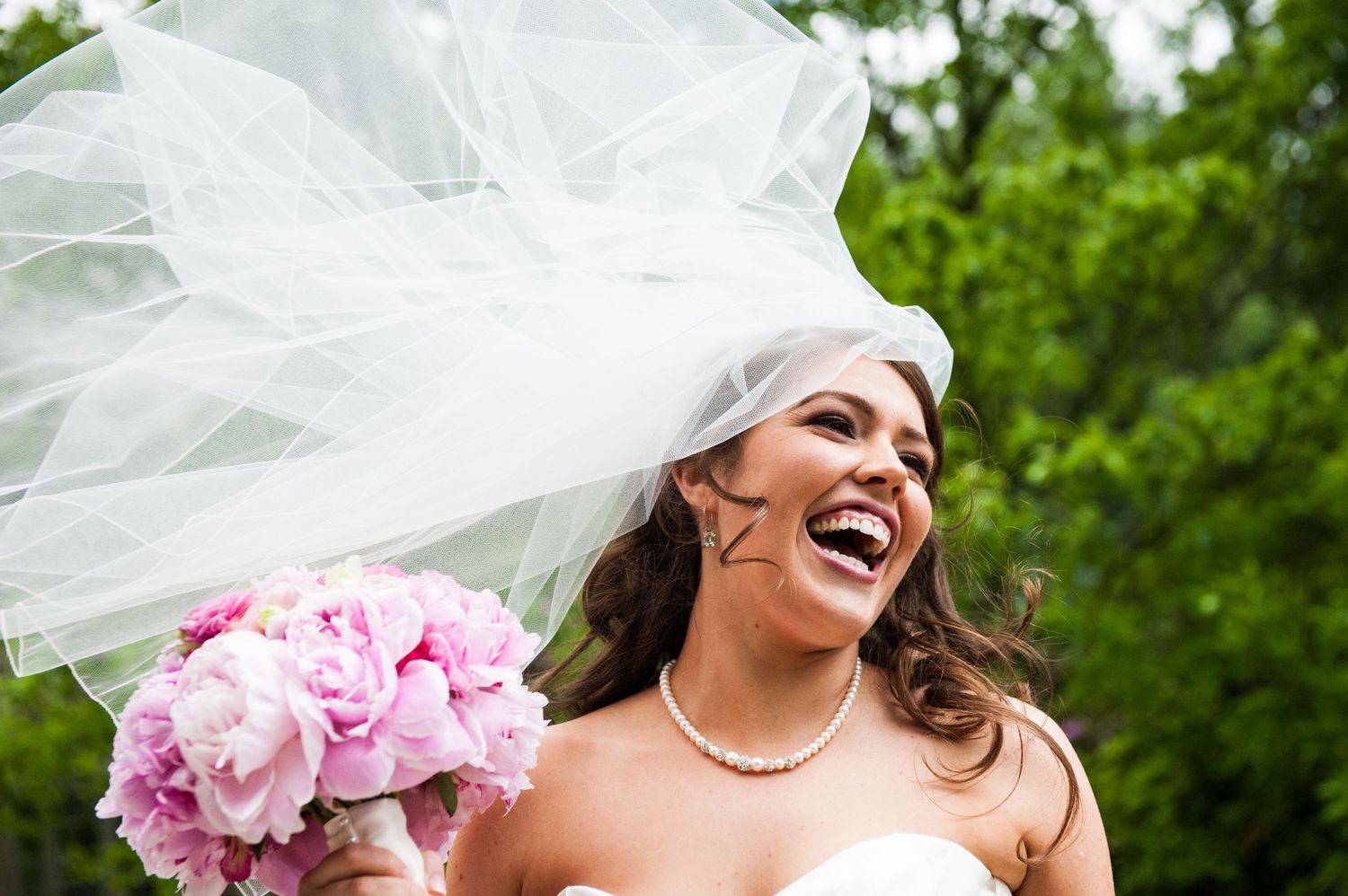 Very happy bride on her wedding day with pink flowers.