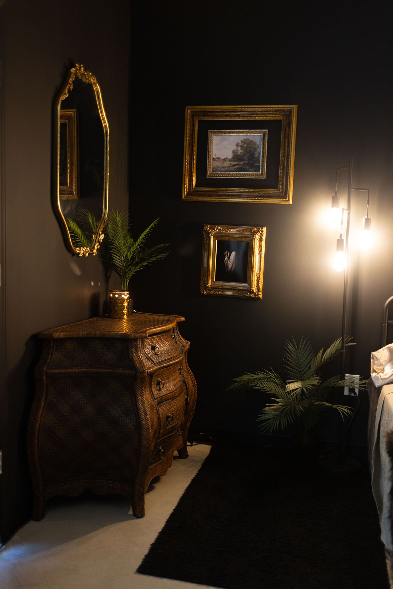 Elegant dark room interior with antique wooden dresser, gold-framed artwork, and soft lighting creating a moody ambiance.