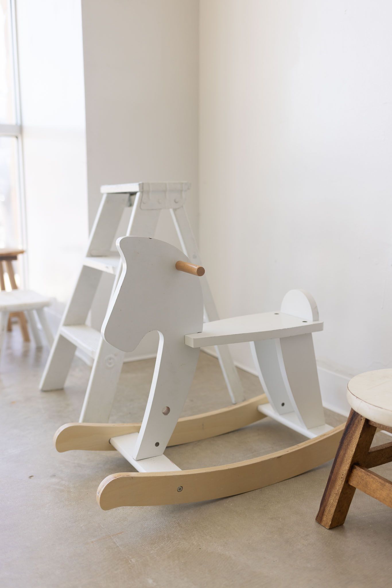 A series of minimalist white rocking chairs with wooden bases shown from different angles in a bright interior space.