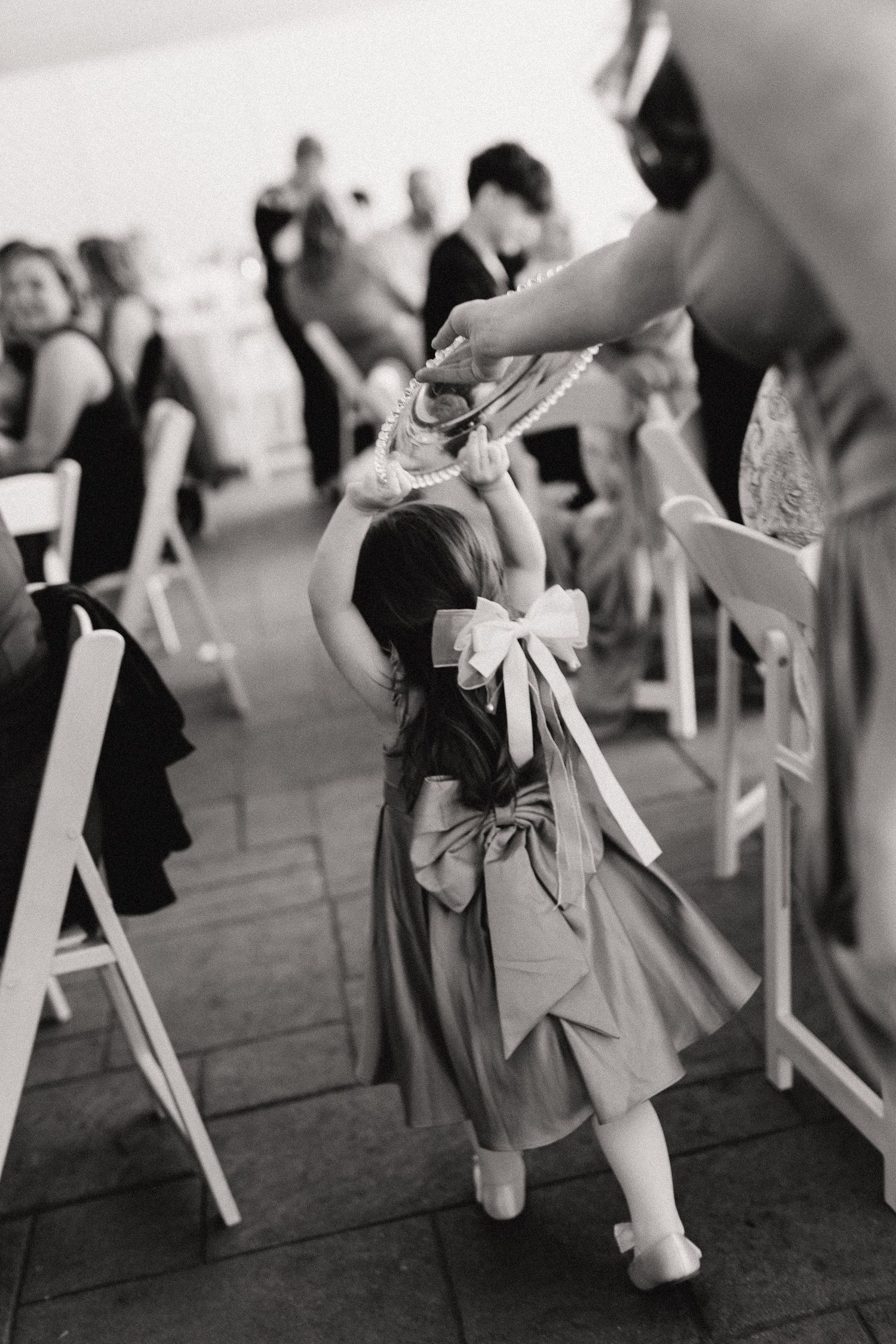 Wedding ceremony chairs decorated with white ribbons arranged in elegant rows at an outdoor venue.