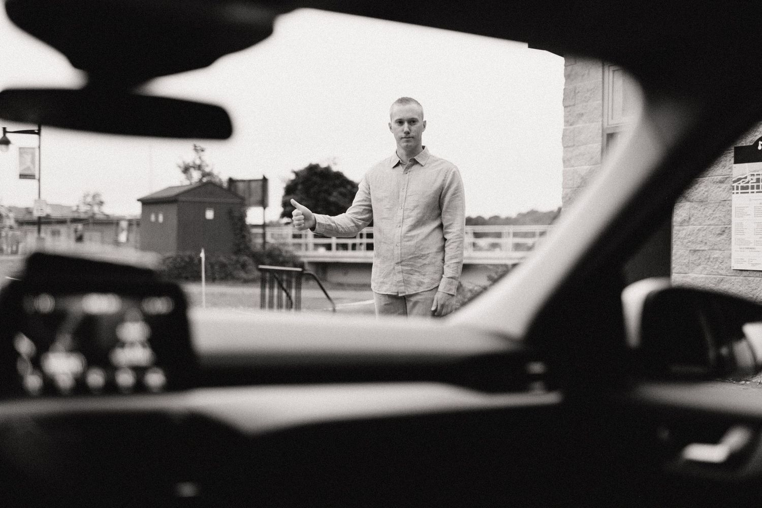 Black and white view through a car window of a street scene.