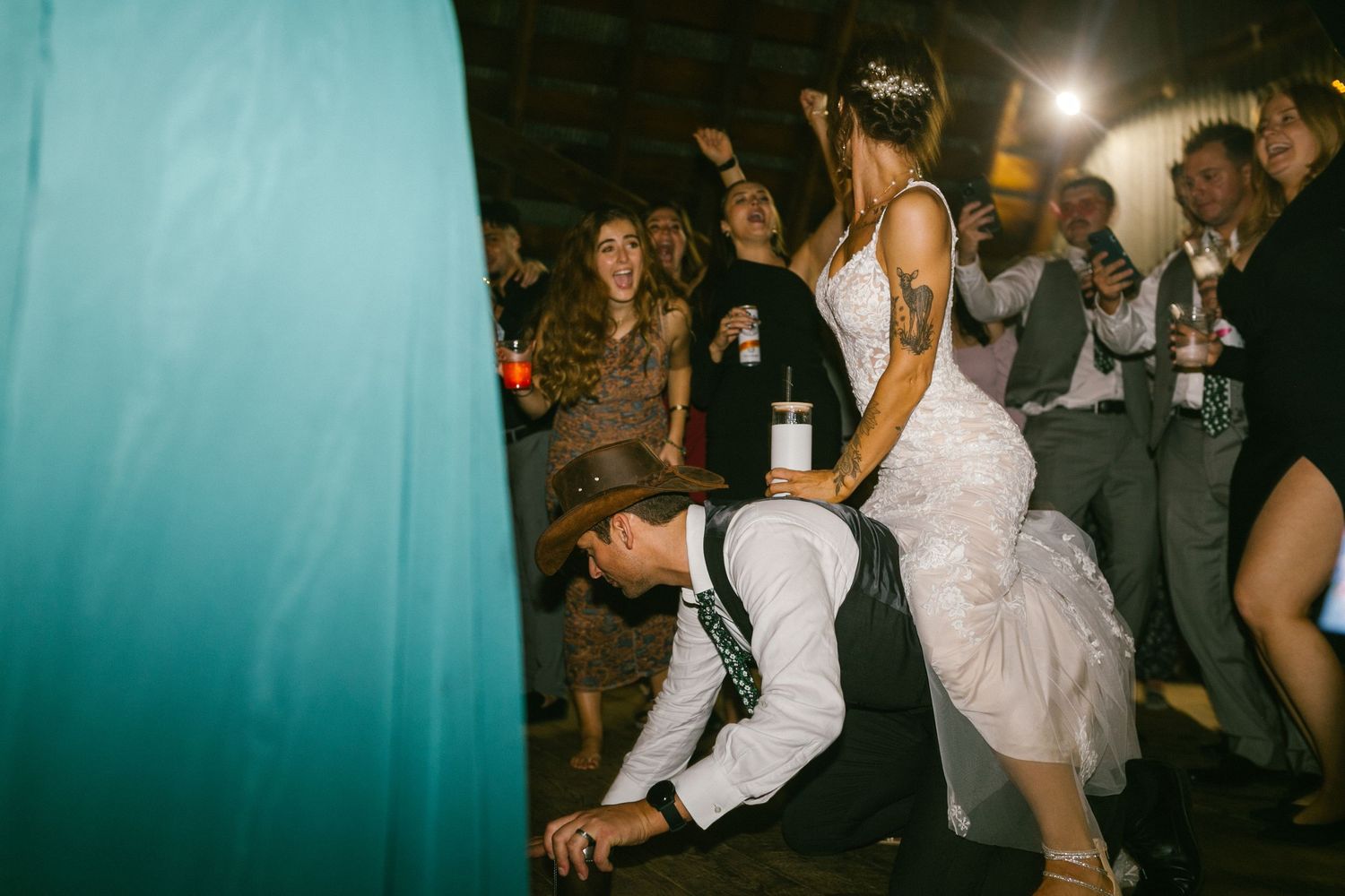 Wedding guests celebrate on a lively dance floor with energetic dance moves at an indoor reception.