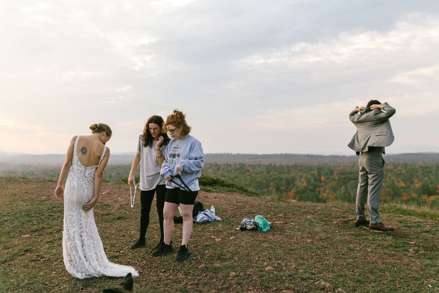 A small group gathers on a hilltop overlooking a scenic natural landscape during golden hour.