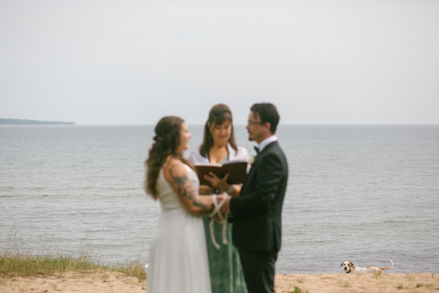 A beach wedding ceremony taking place along the shoreline at sunset.